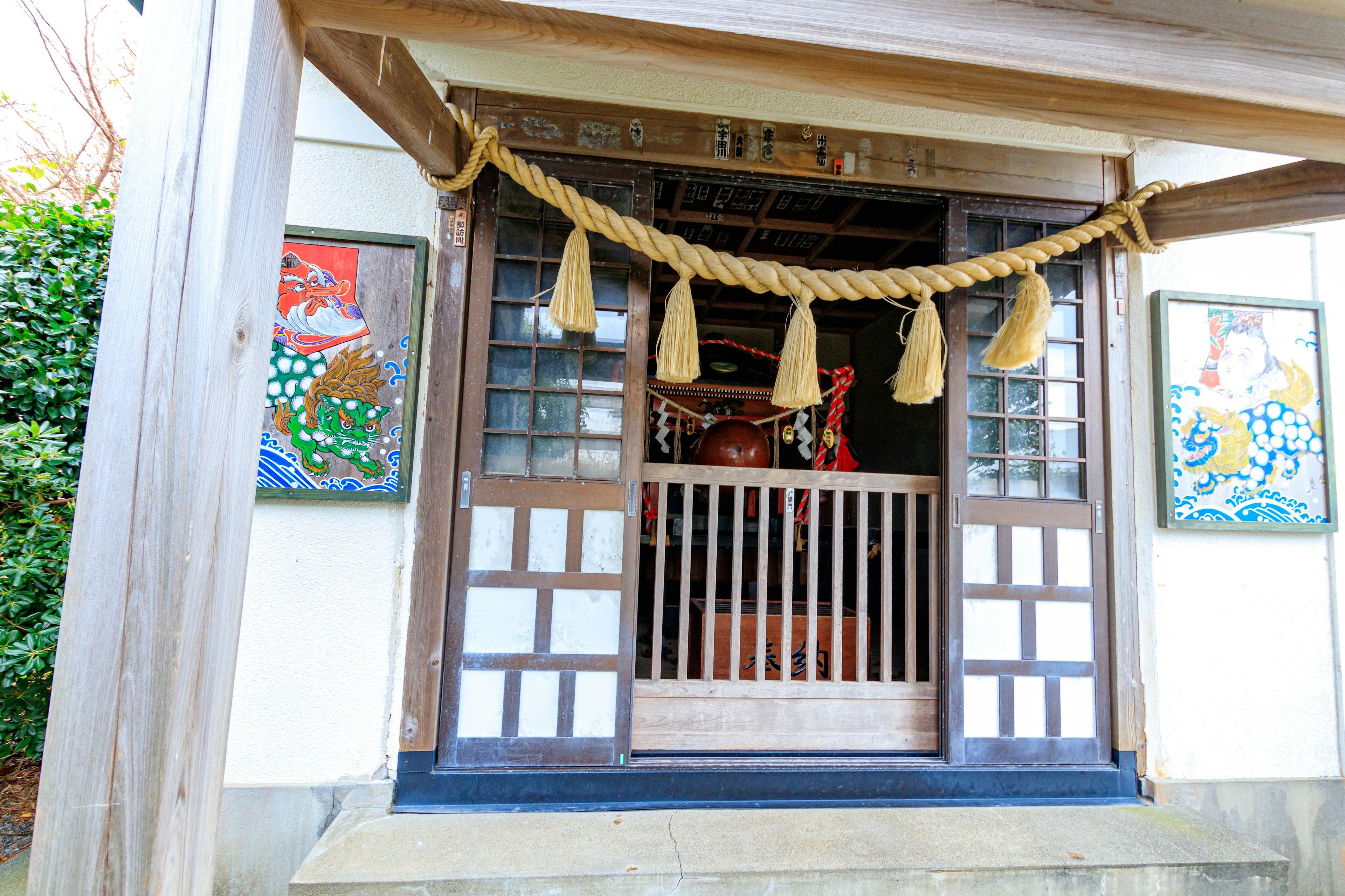 Entrance of a traditional Japanese building adorned with a rope and colorful paintings