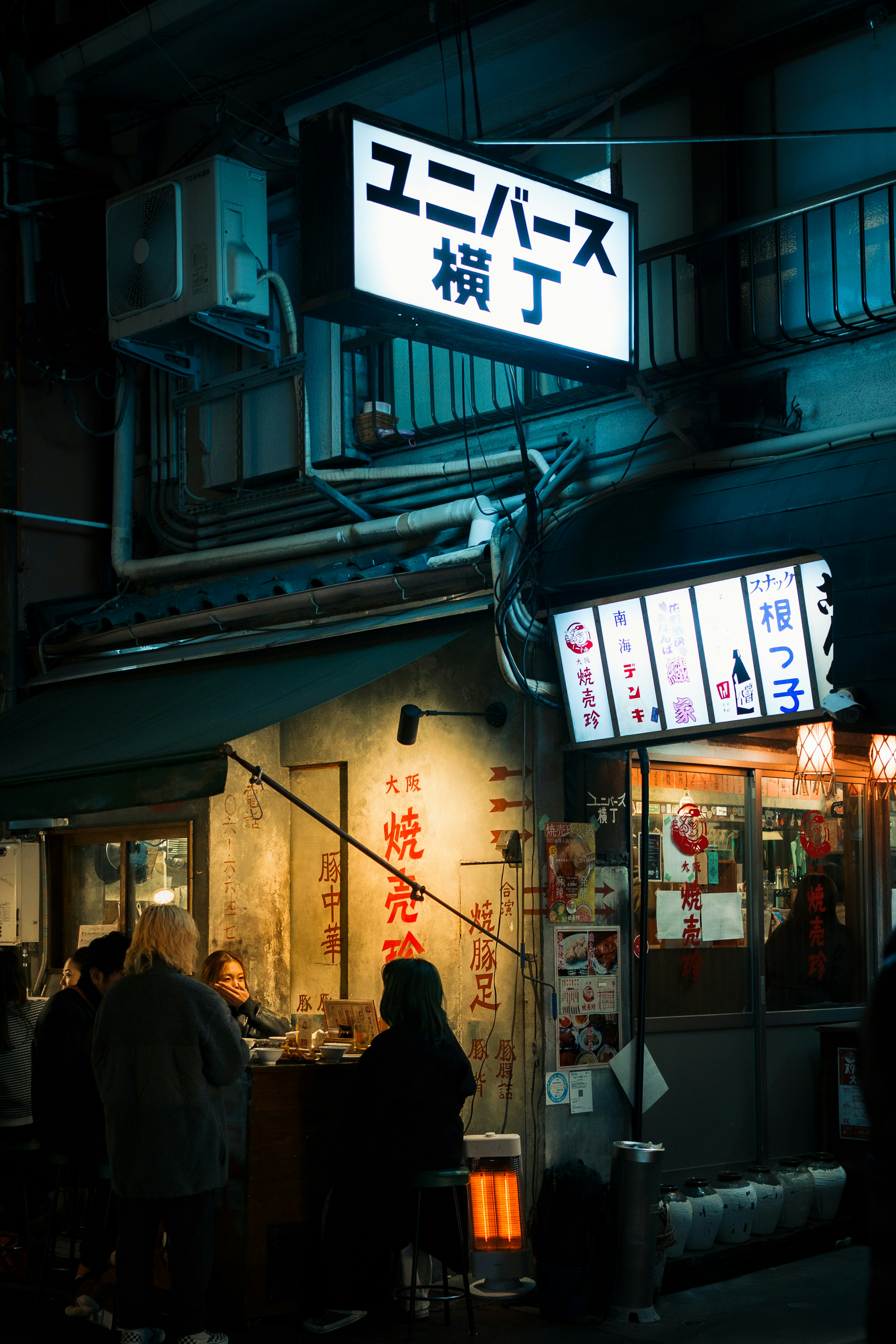 Night view of Universe Alley with bustling patrons and storefronts