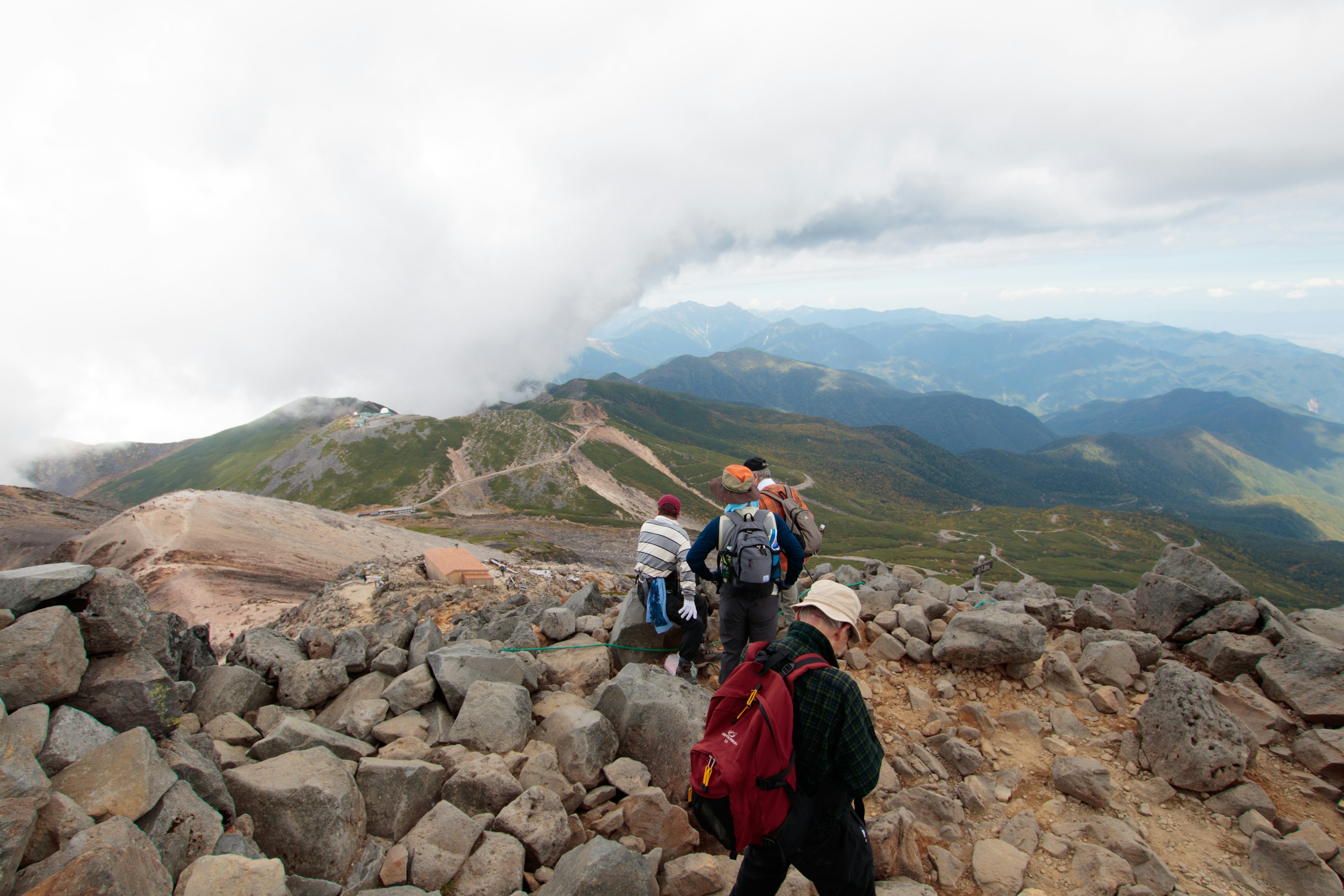 Randonneurs marchant près du sommet de la montagne avec un paysage nuageux