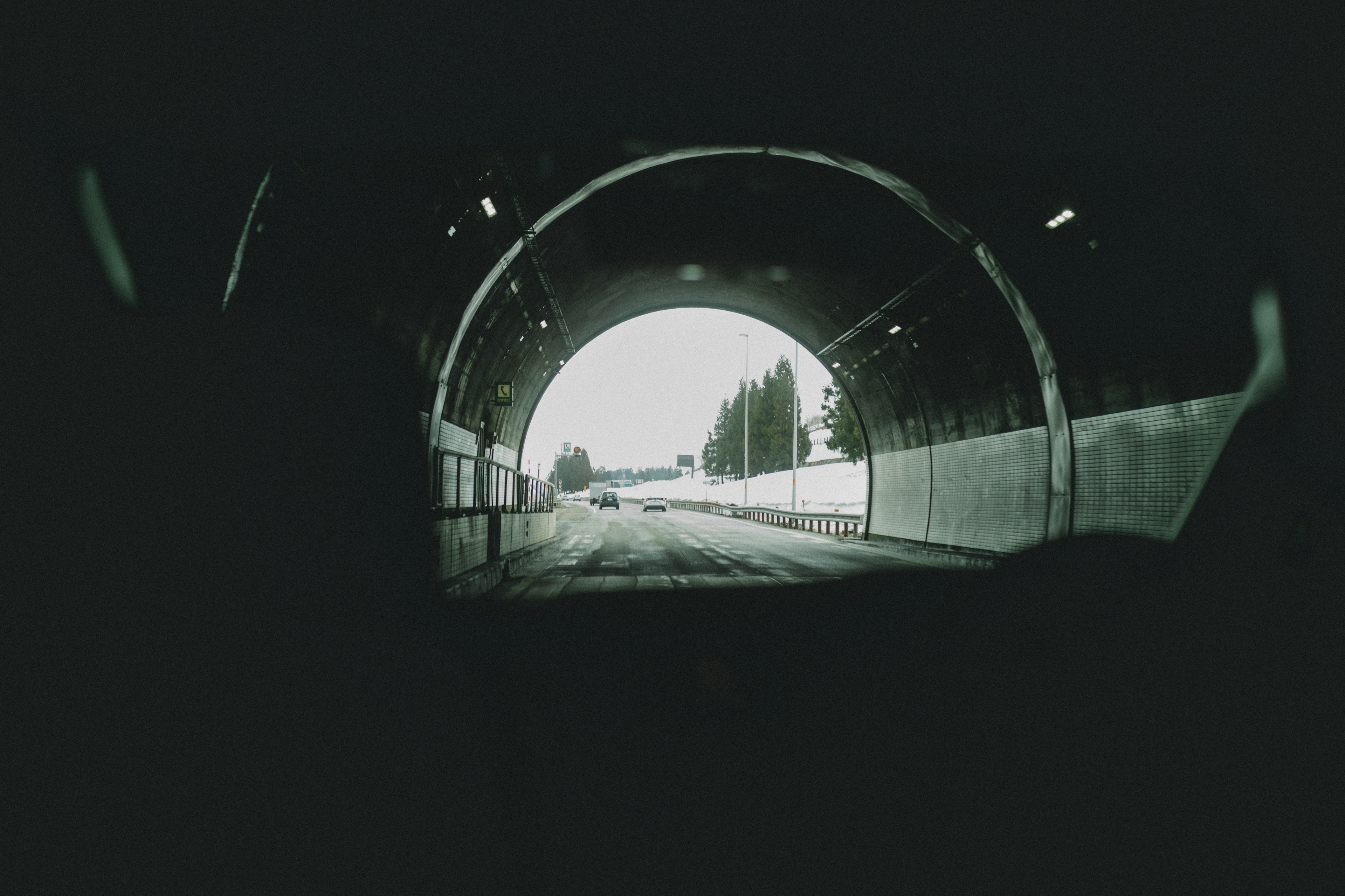 Interno scuro di un tunnel con uscita e strada visibili