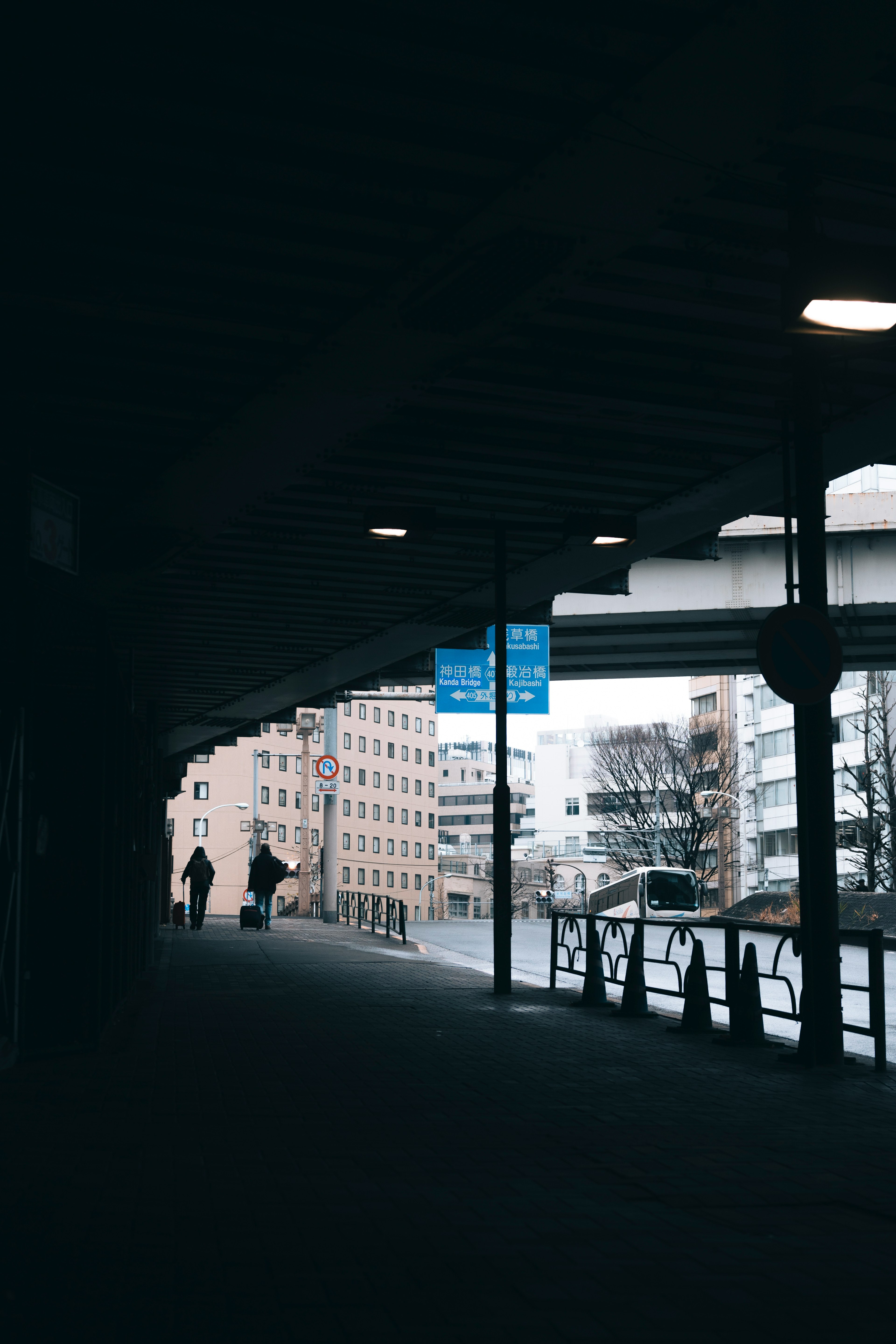 暗い通路に人々が歩いている様子と青い看板が見える風景