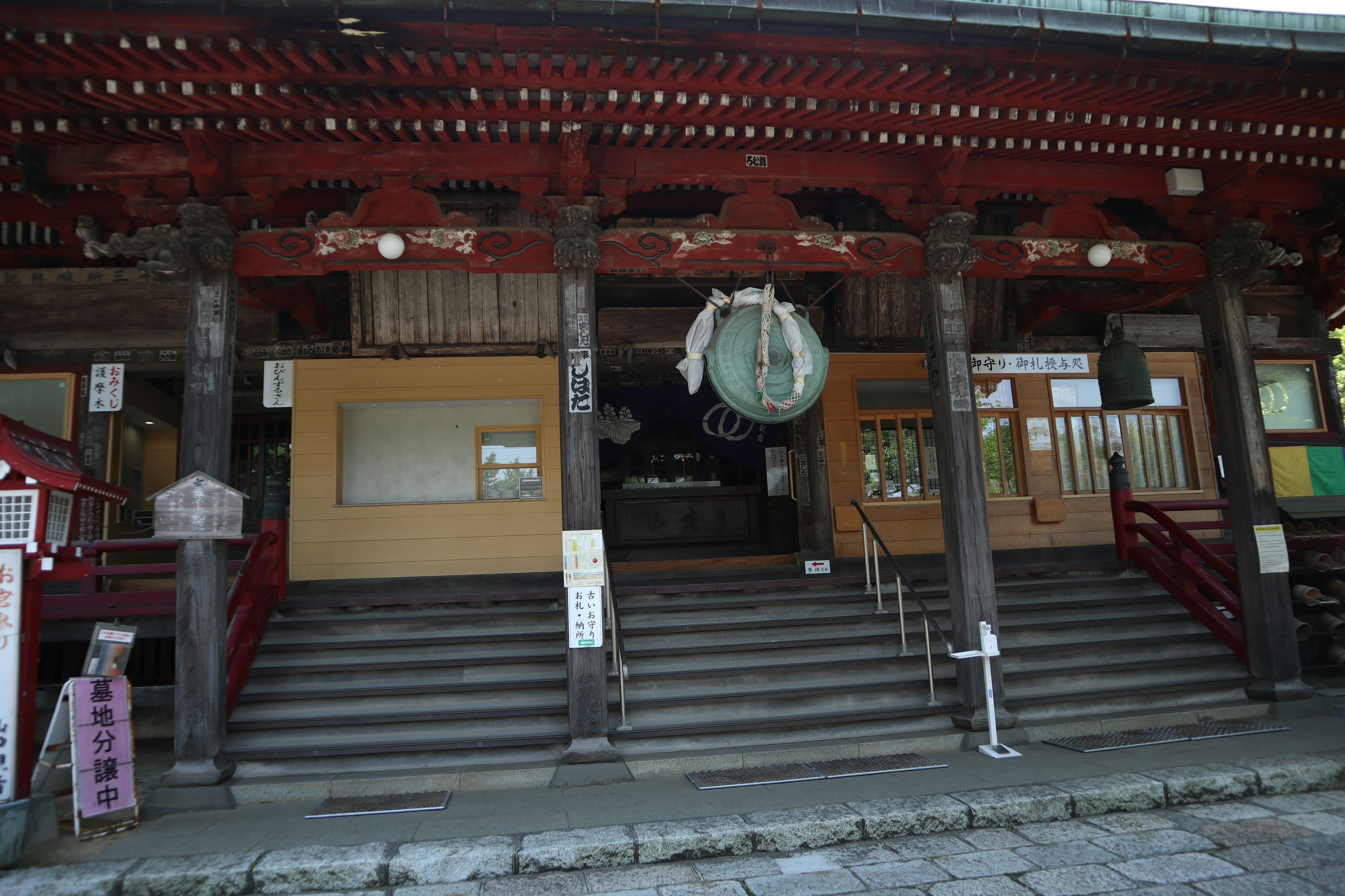 Entrée d'un temple avec toit rouge et piliers en bois