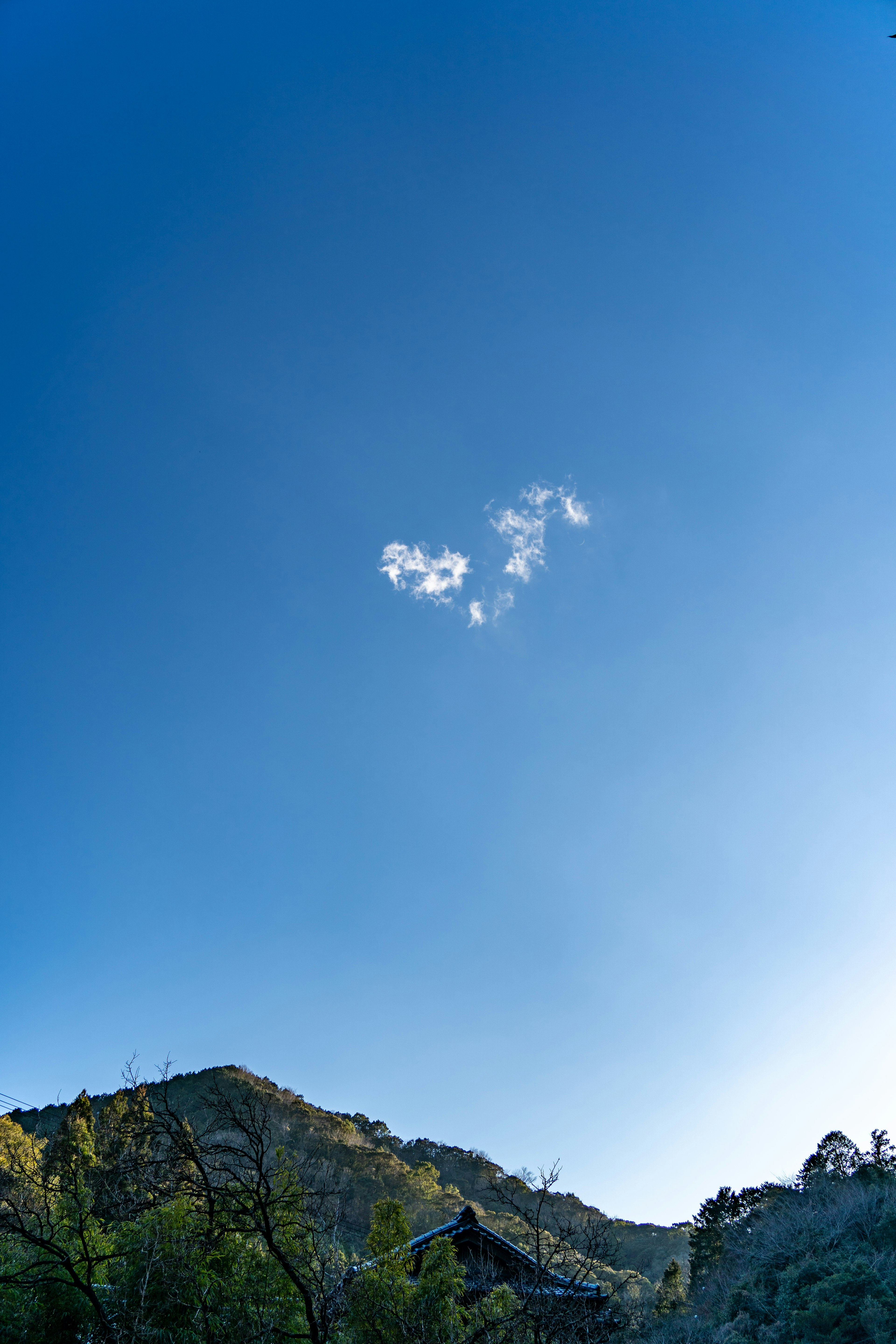 青空に浮かぶユニークな形の雲と山の風景