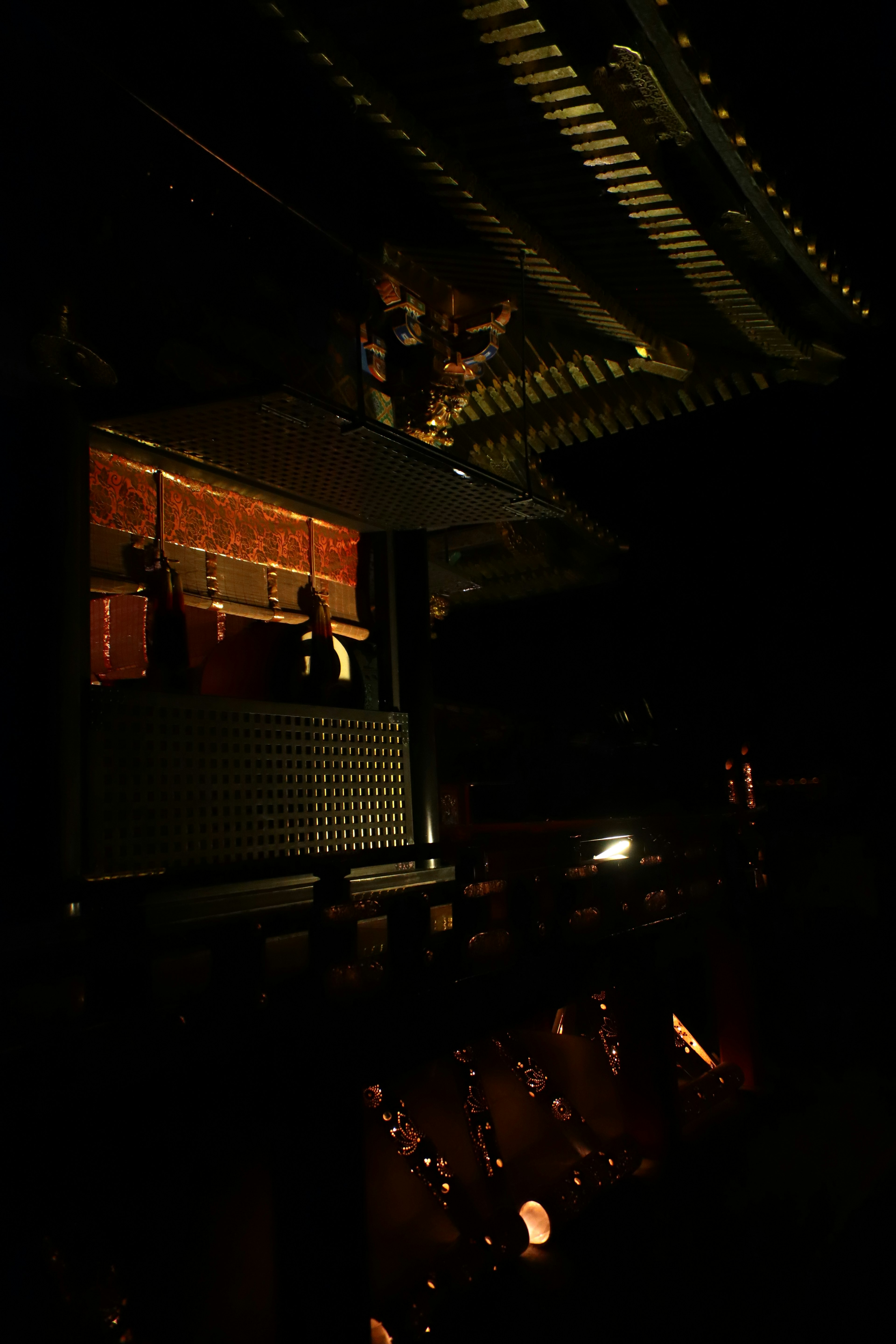 Vista nocturna de una estructura de templo con balcón de madera iluminado