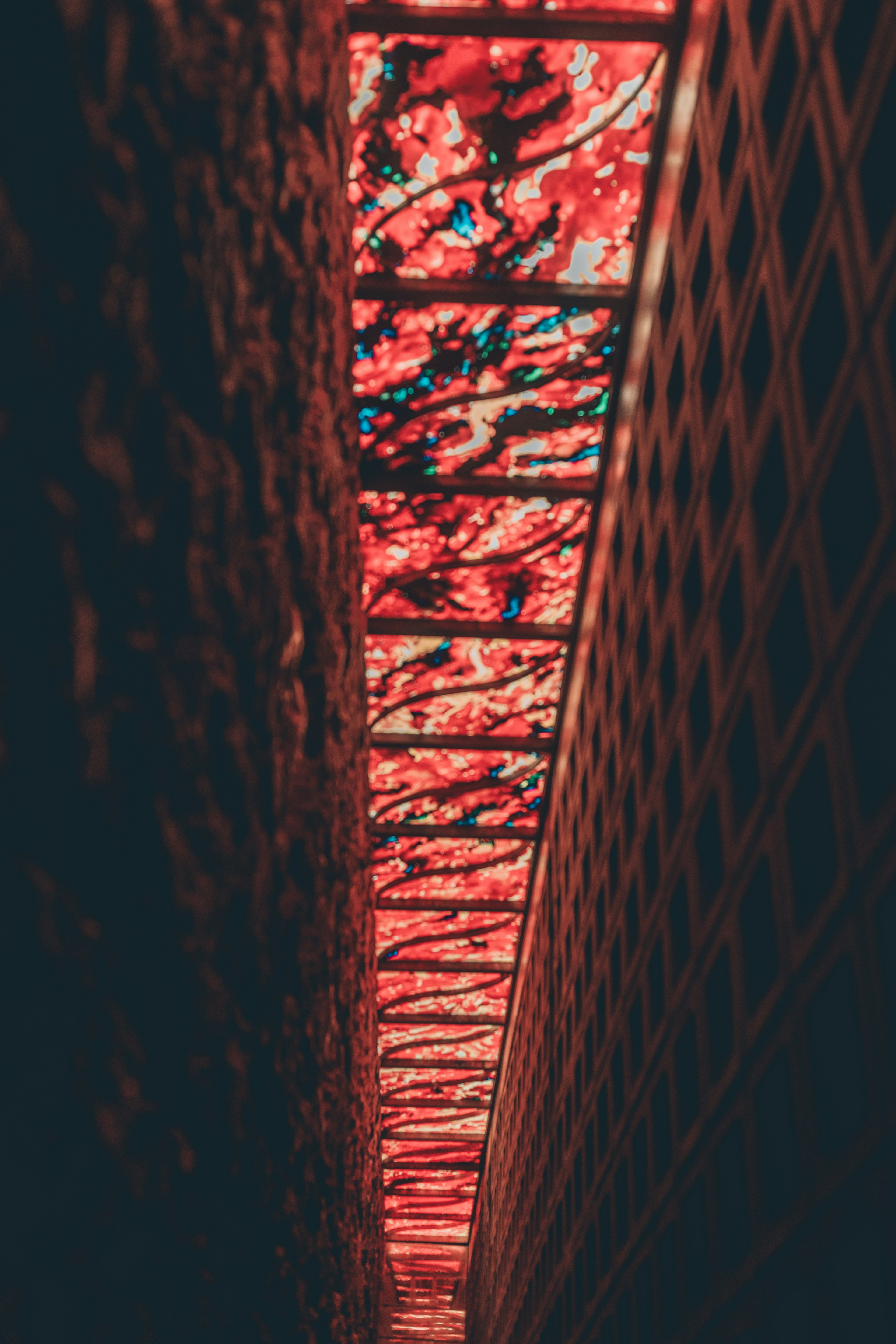 Narrow passage illuminated by red light featuring patterned glass panels