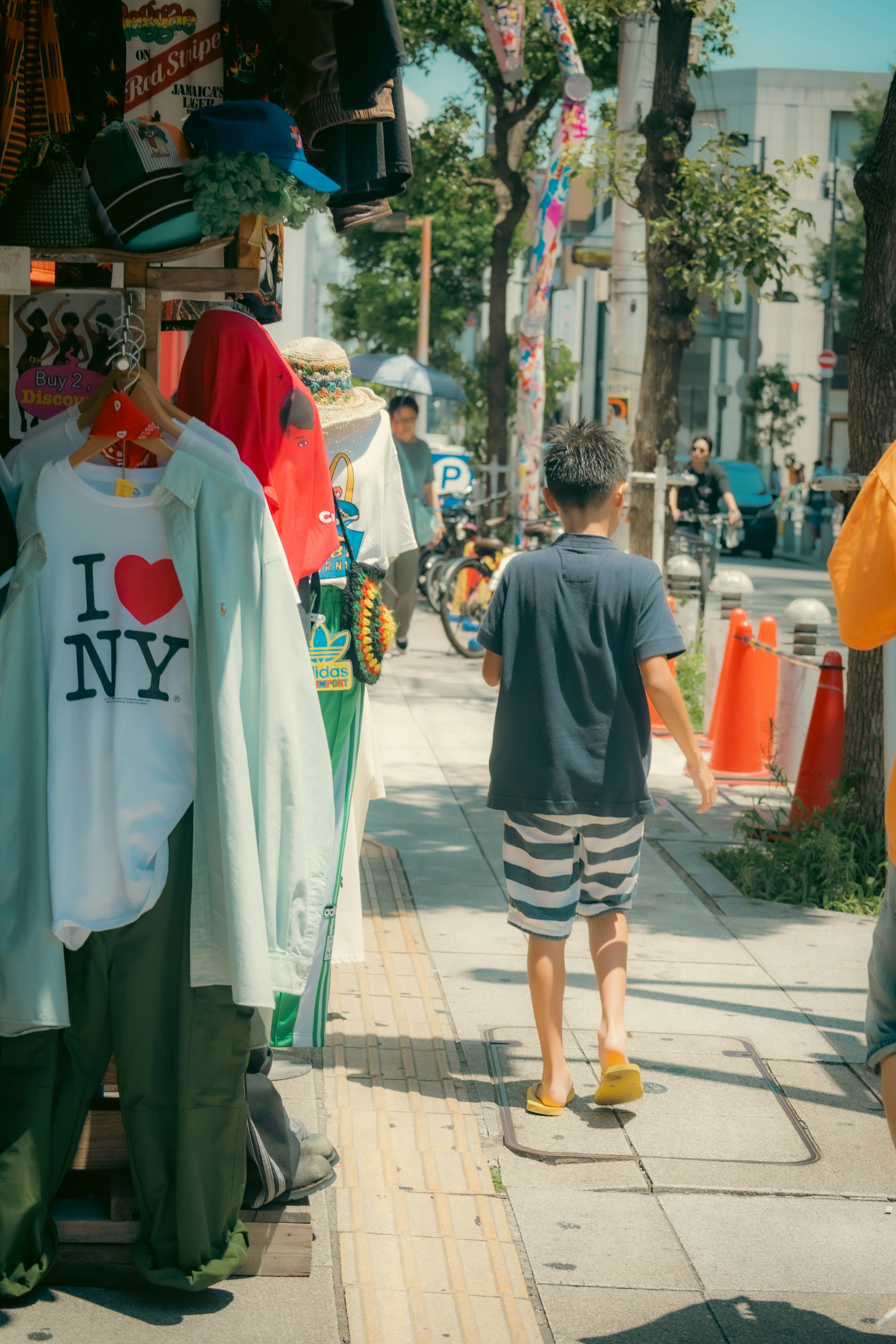 街の通りにある服屋の前で歩く少年とカラフルな服