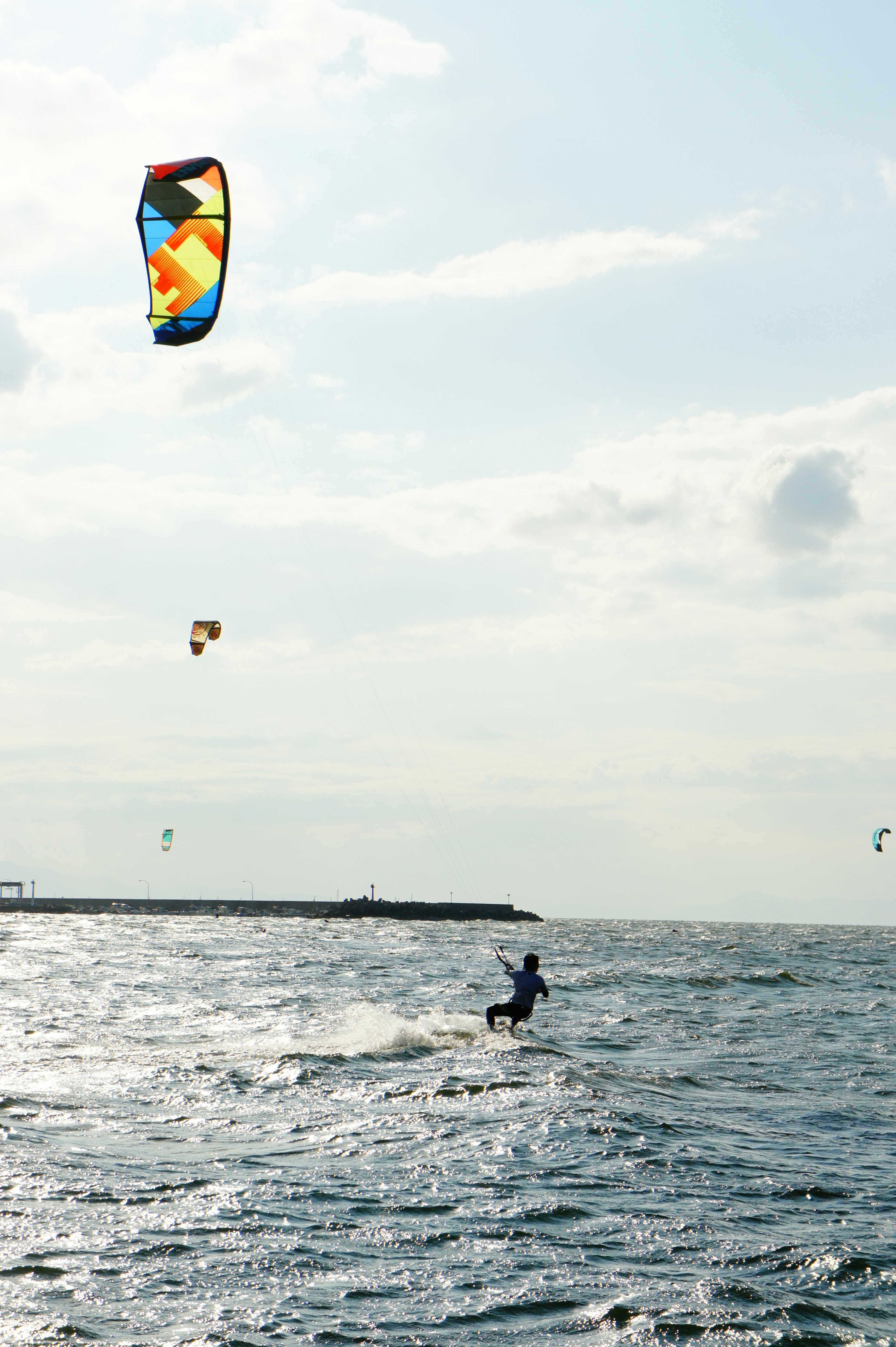 Una persona haciendo kitesurf con un cometa colorido en un entorno oceánico sereno