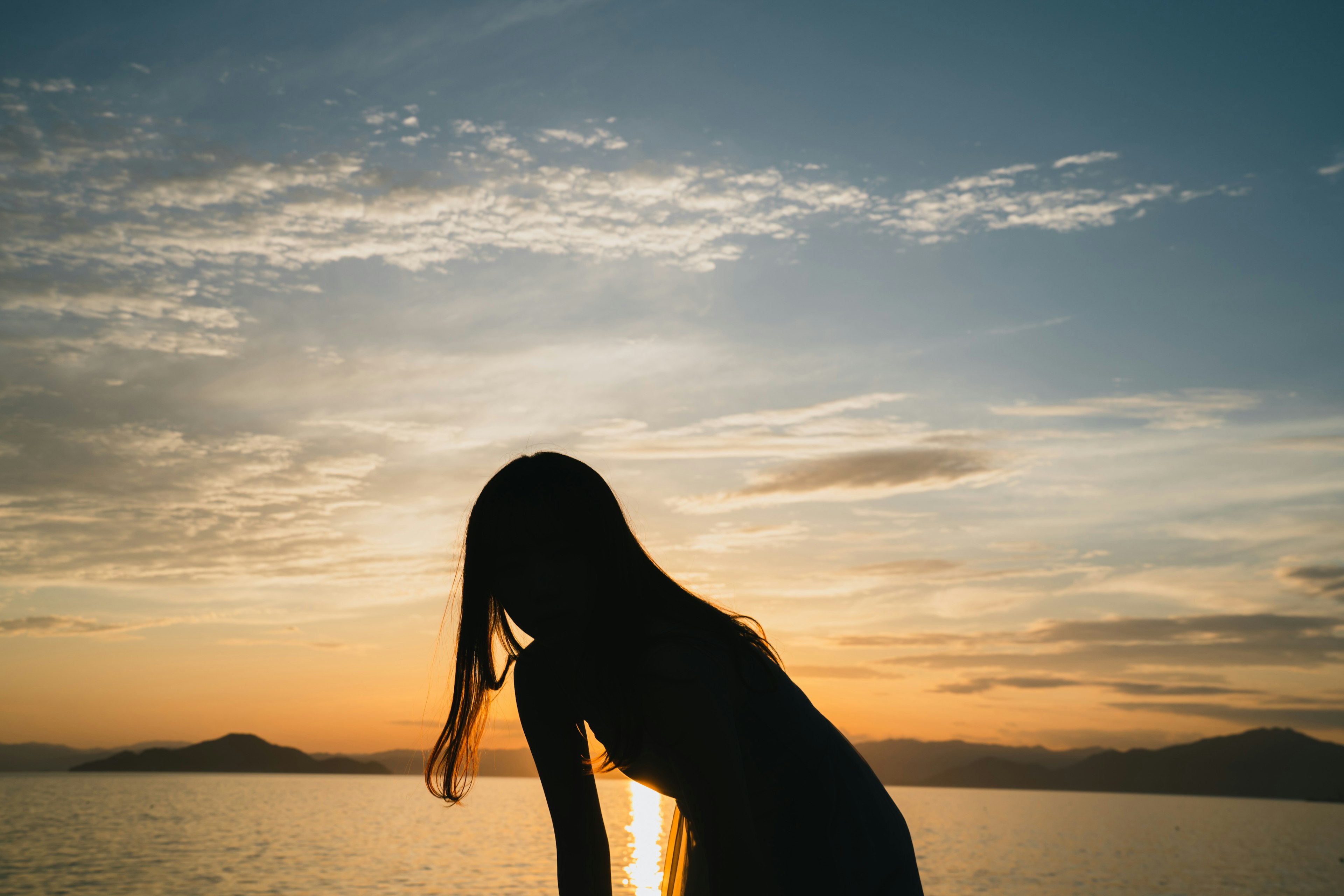 夕日を背にした女性のシルエットが美しい海の風景