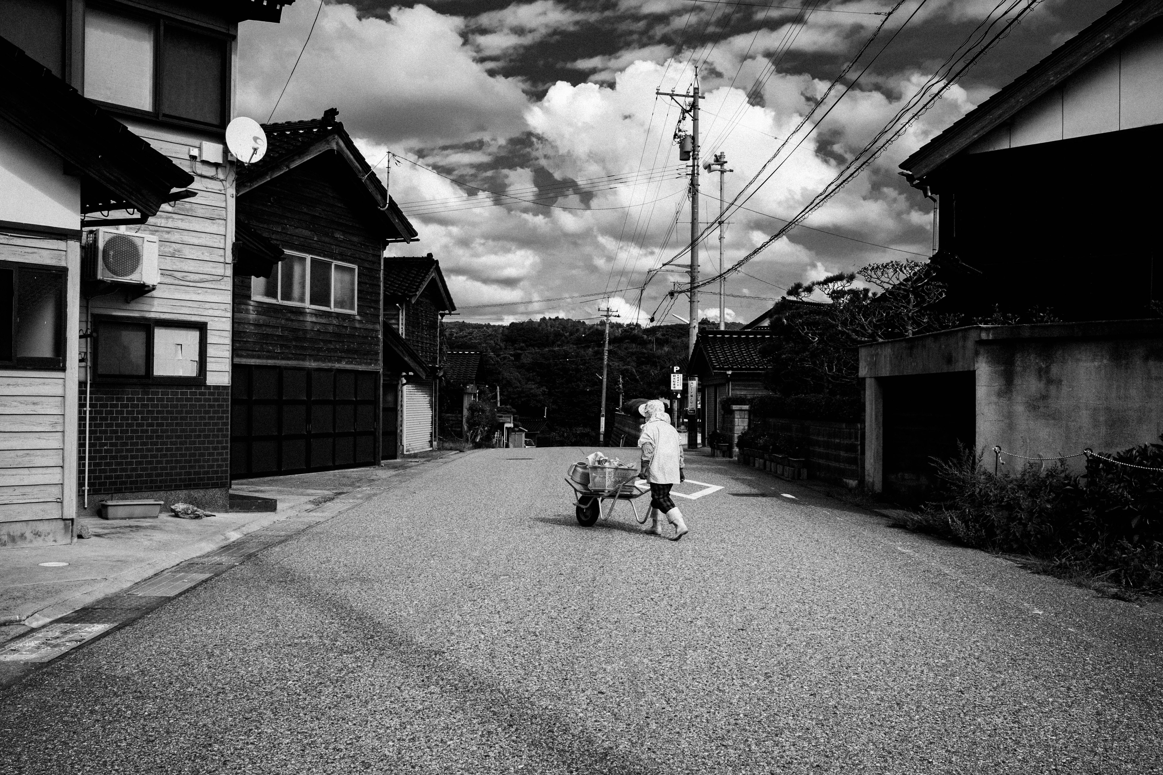 白黒の道路を歩く子供とカート周囲は静かな住宅街