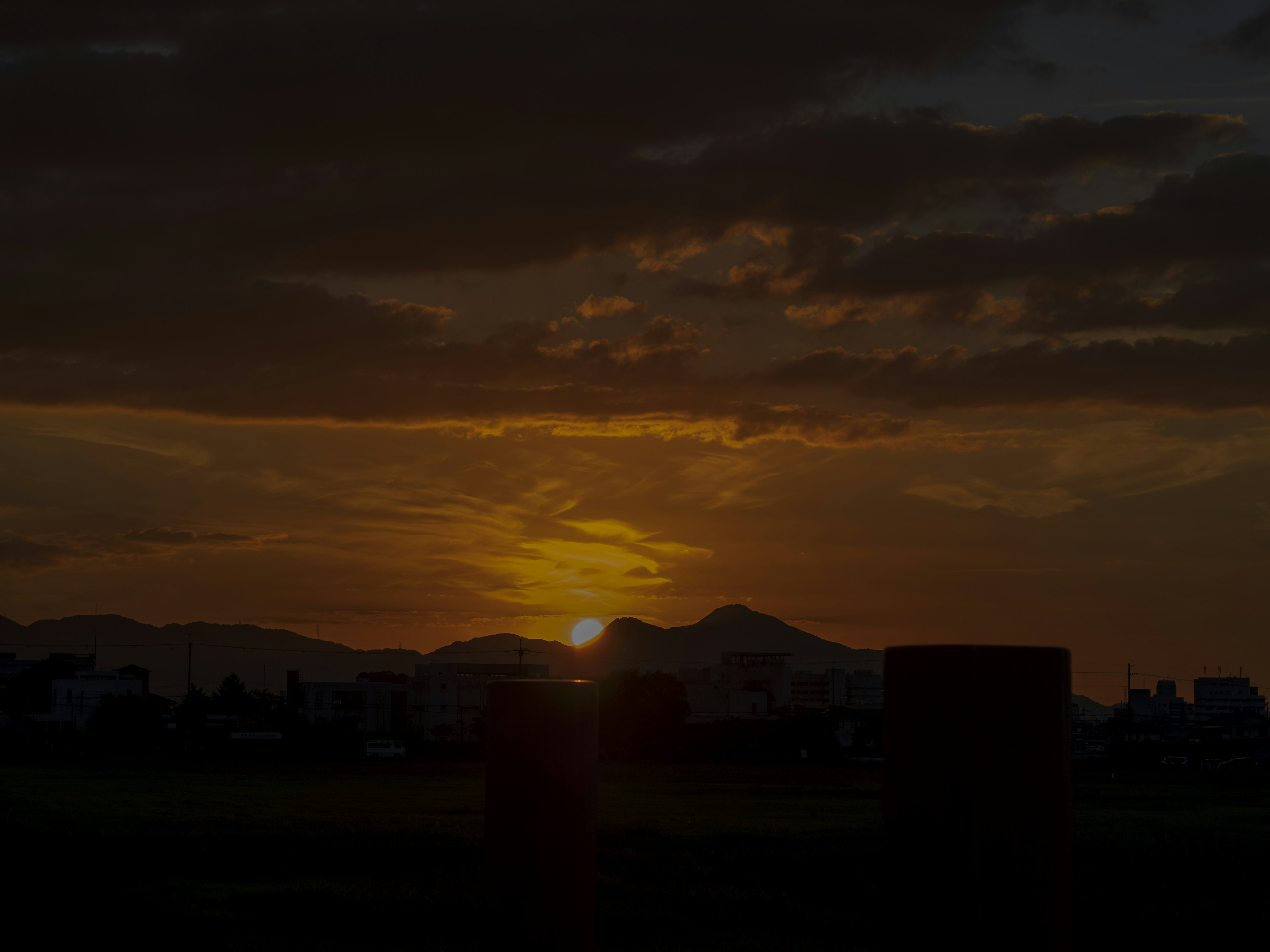 夕日が山の背後に沈む風景と雲が広がる空