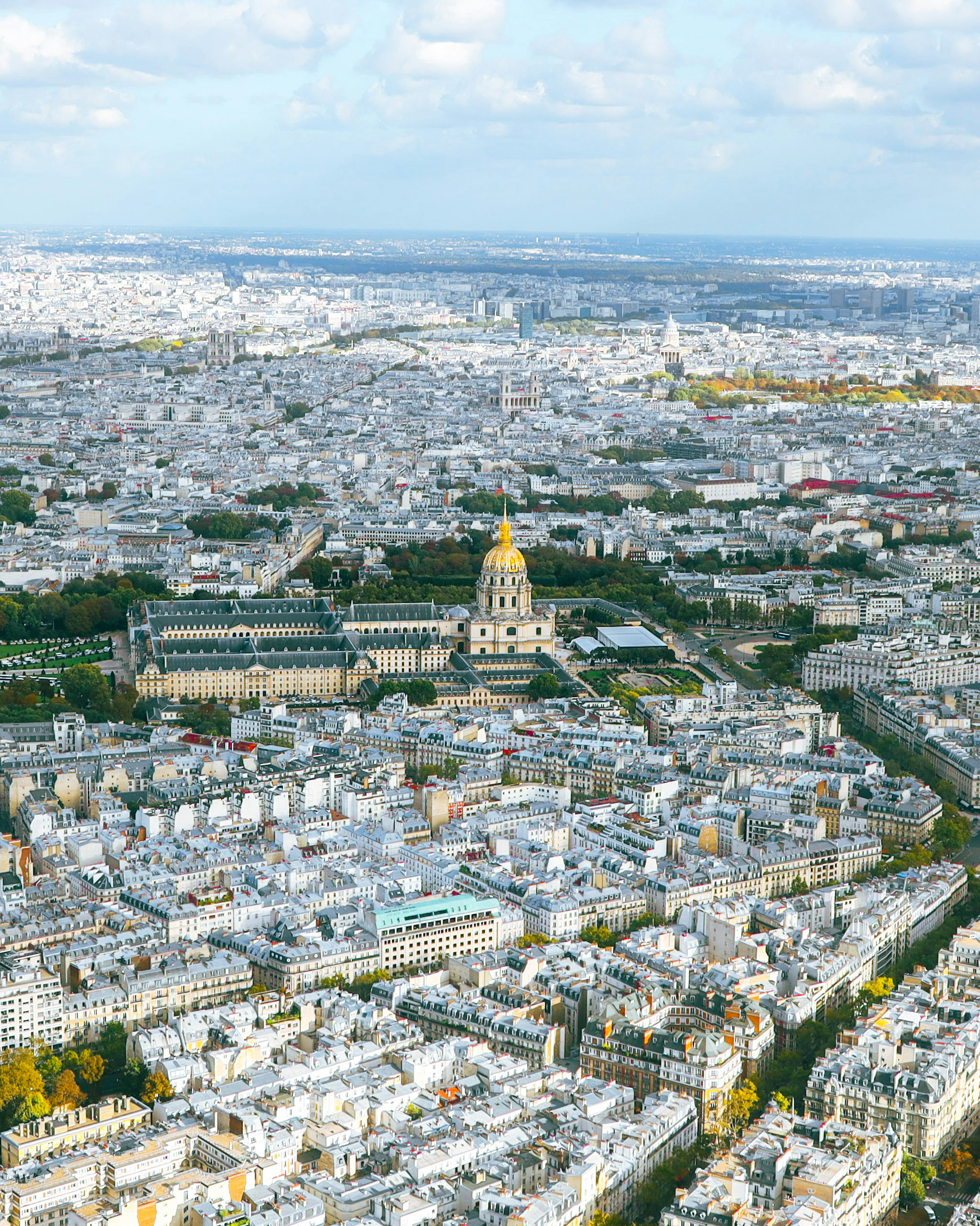 Aerial view of Paris showcasing rooftops and the golden dome of Les Invalides