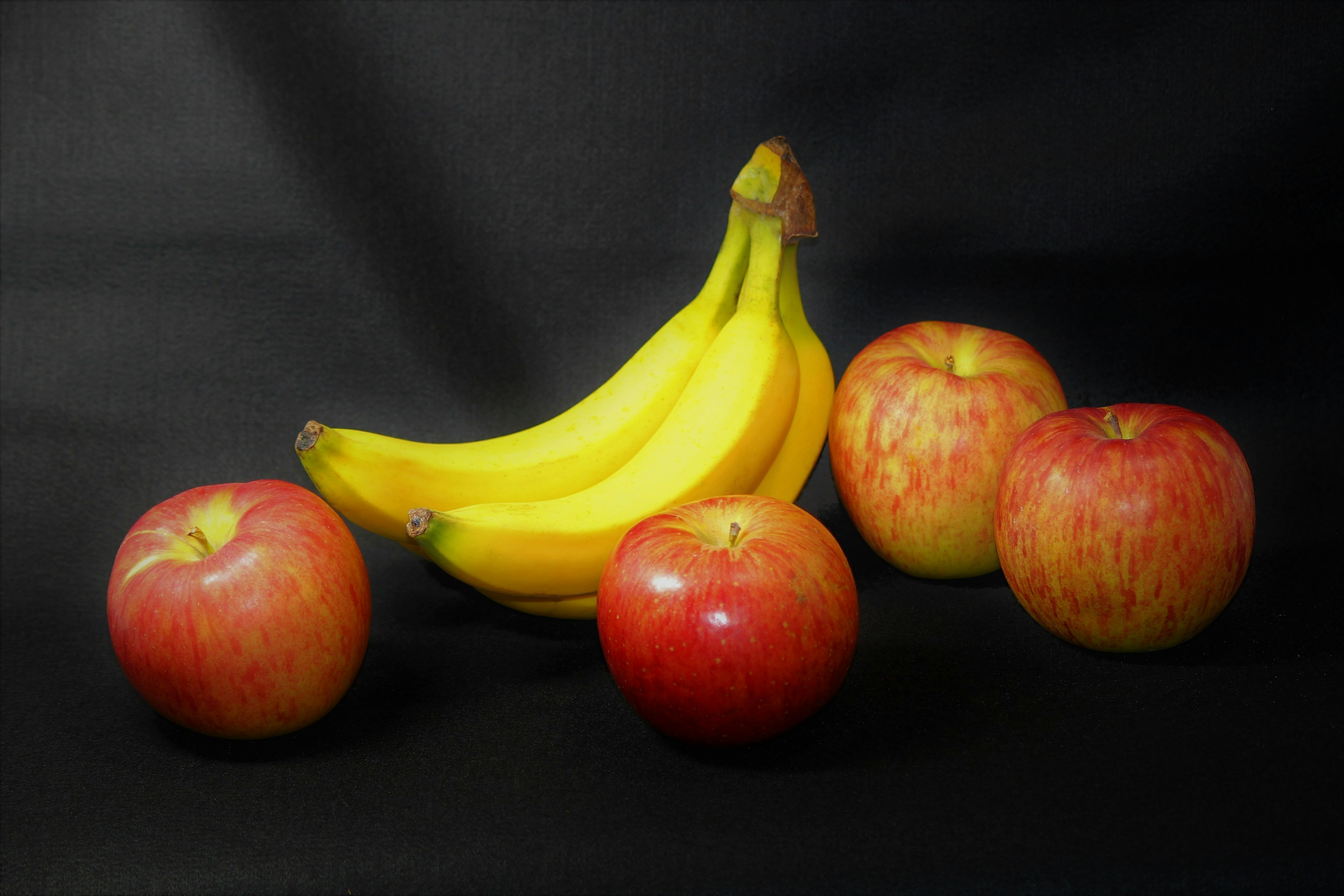 Nature morte de pommes rouges et de bananes jaunes sur un fond noir