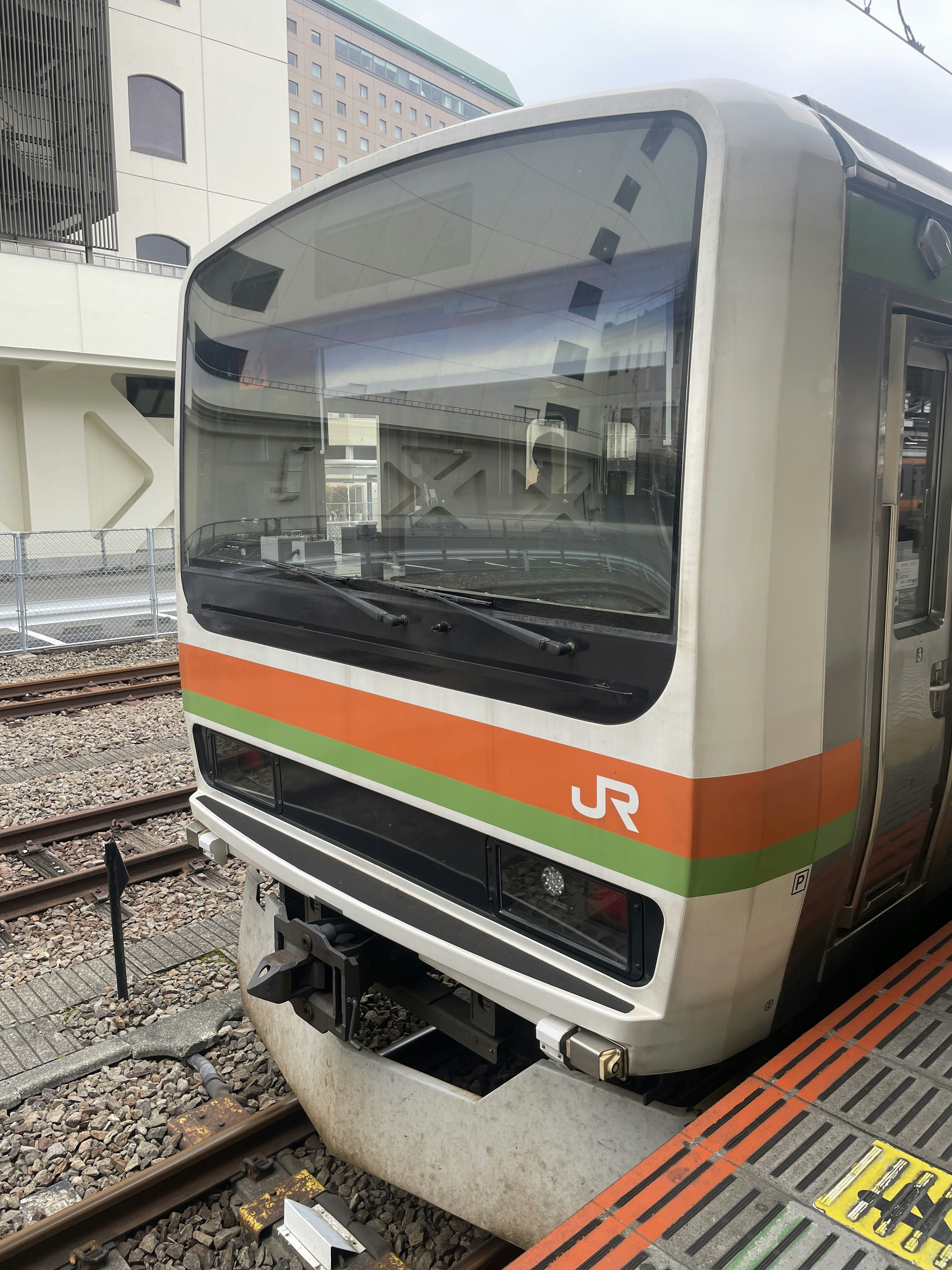 Vue de face d'un train JR avec des rayures orange et verte distinctives