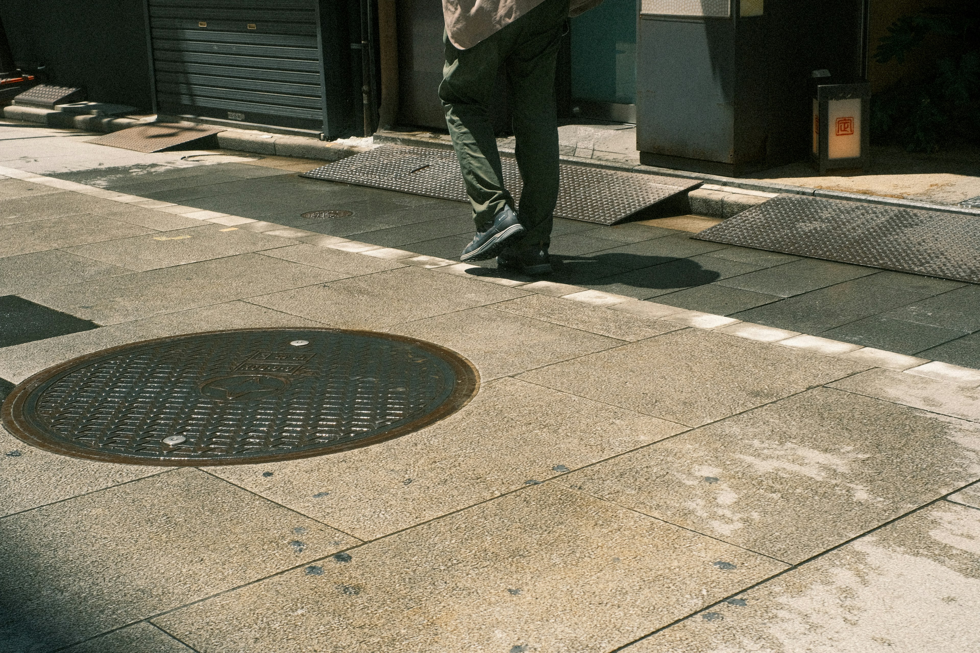 Una persona caminando en una calle pavimentada con una tapa de alcantarilla