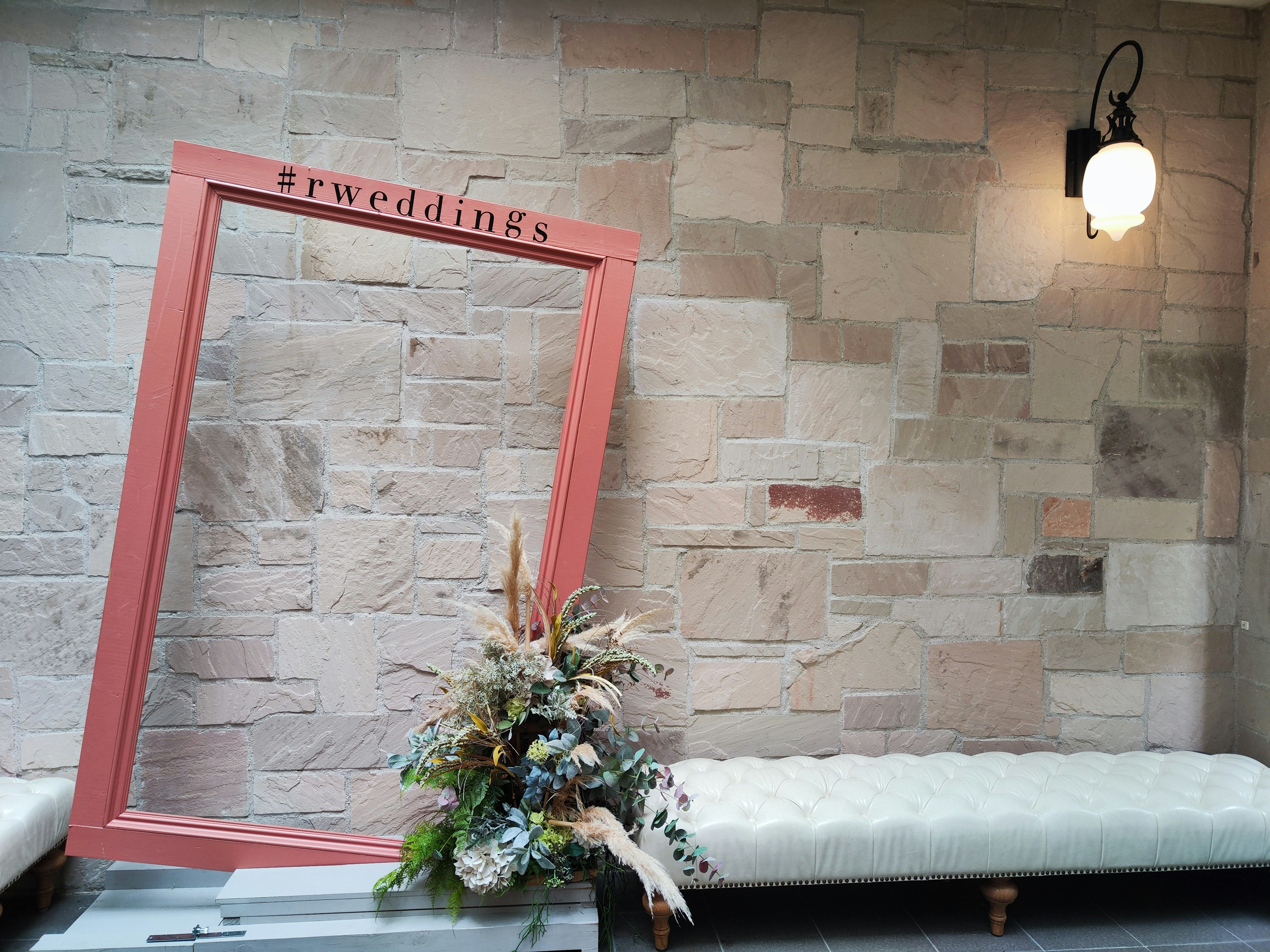 Intérieur avec un cadre corail et un arrangement floral sur un mur en pierre