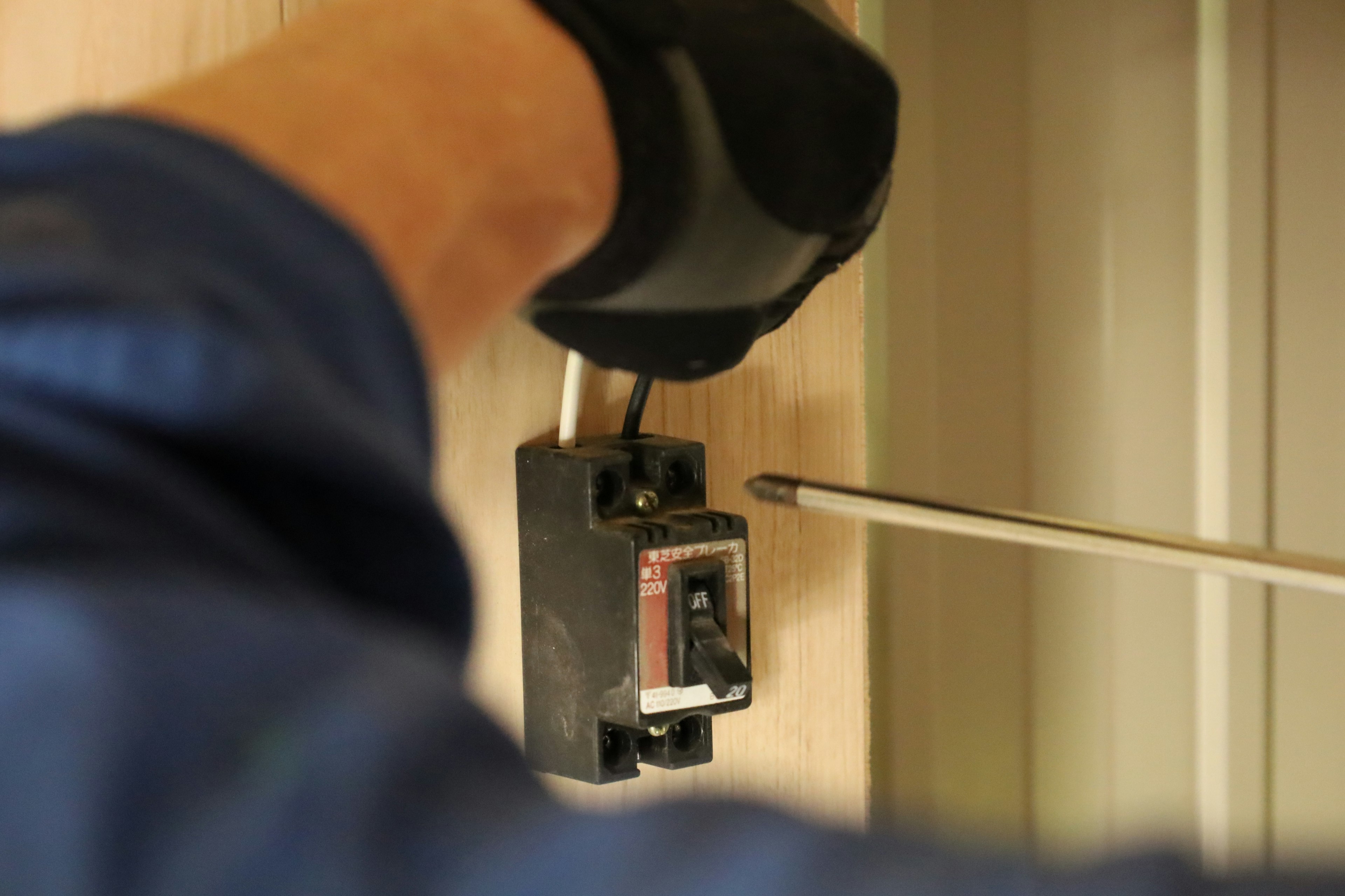 A gloved hand working on a circuit breaker