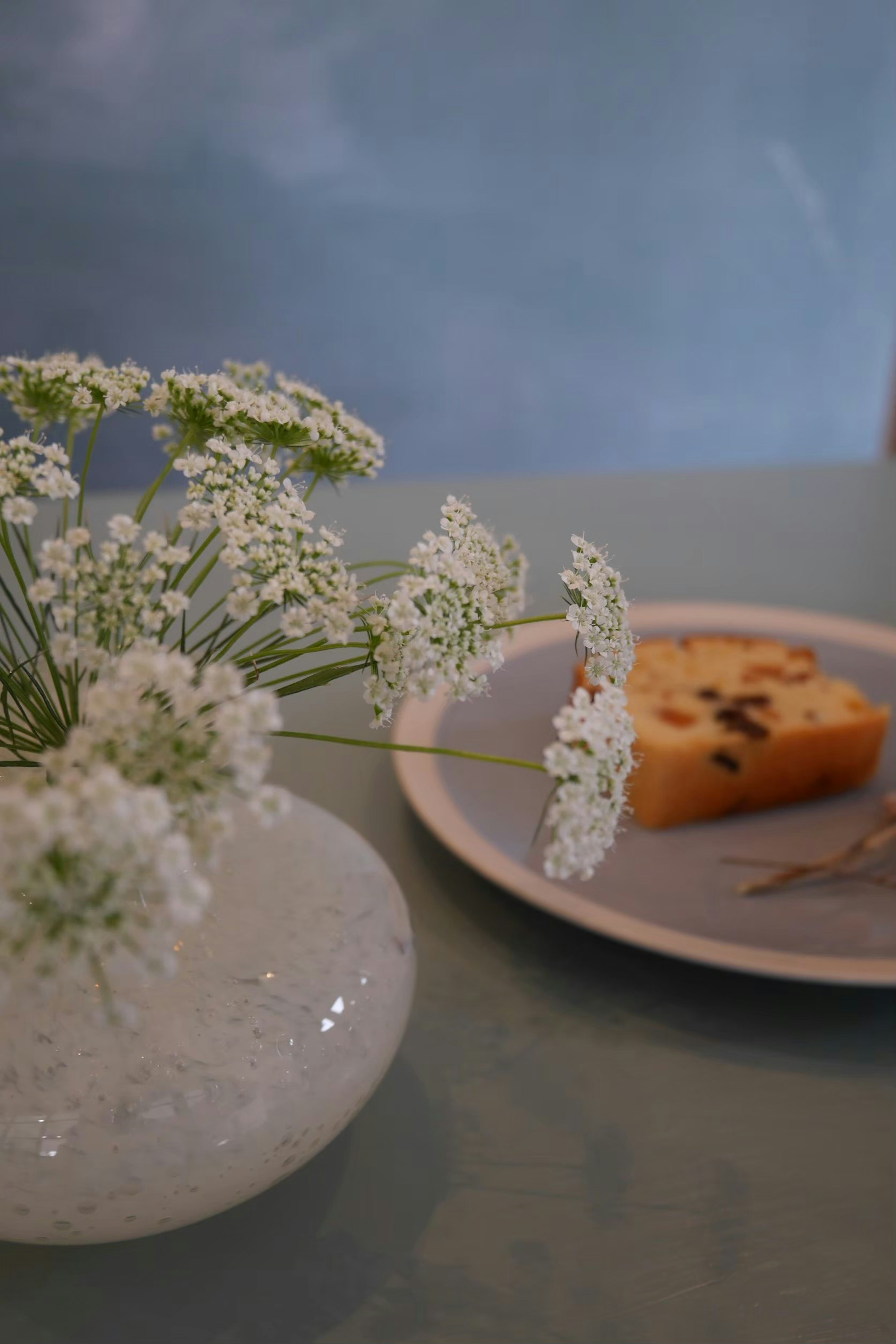 Eine Vase mit weißen Blumen und ein Stück Kuchen auf einem Teller