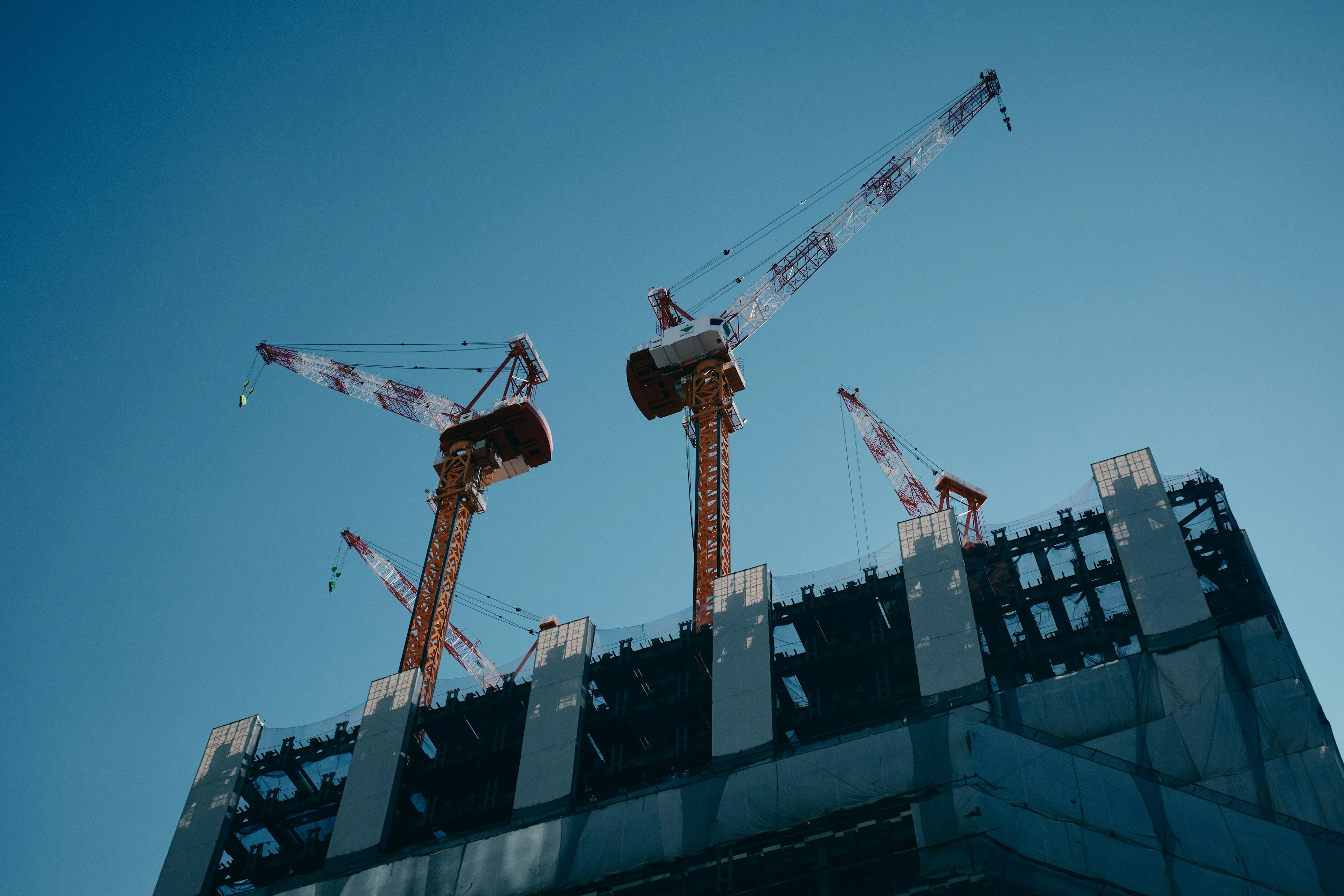 Construction site of a skyscraper with cranes under a blue sky