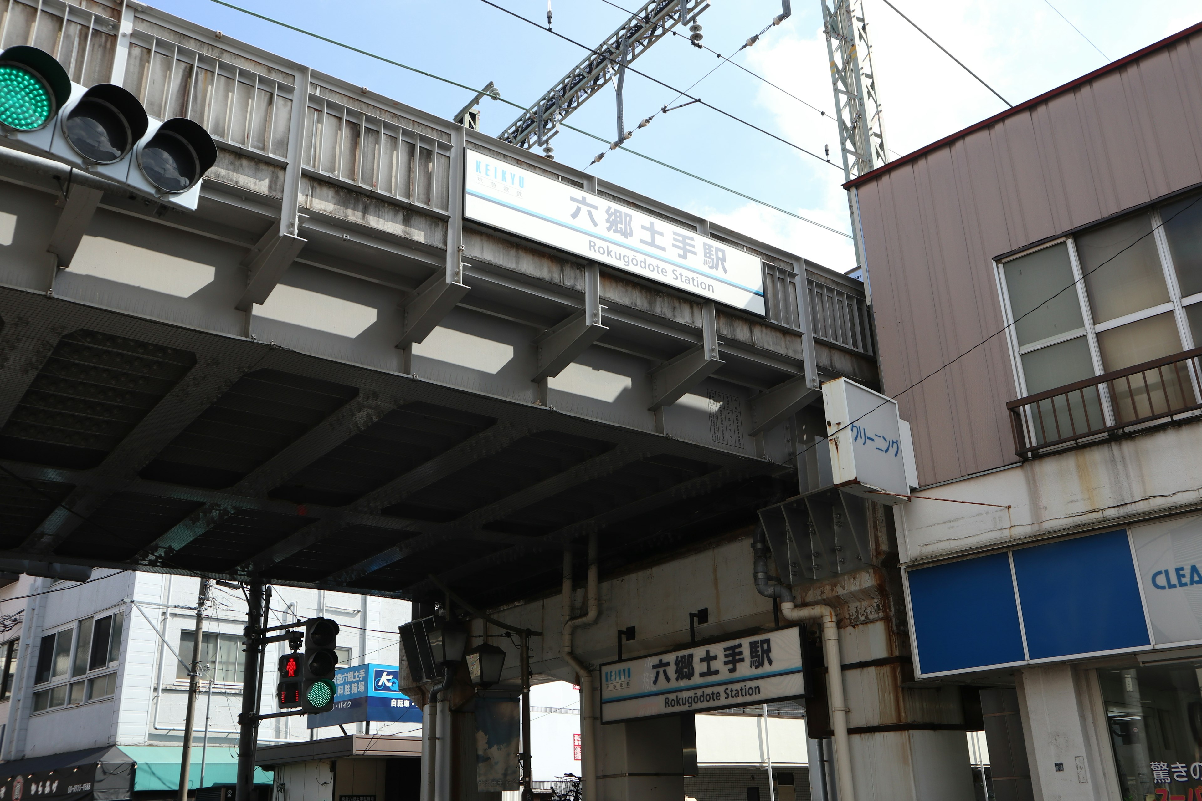 Semafori e insegna della stazione sotto un viadotto ferroviario