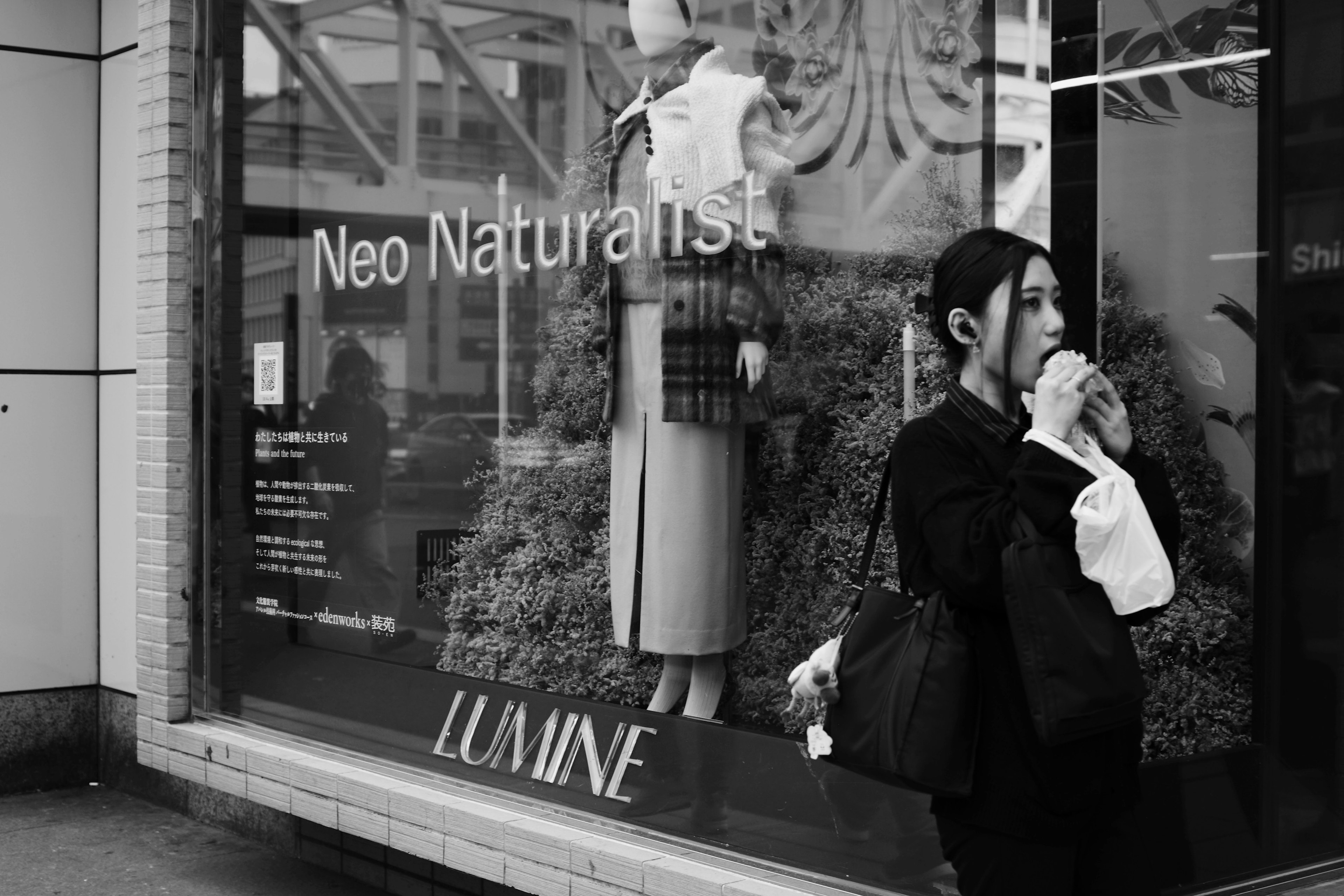 Femme buvant un café dans un paysage urbain en noir et blanc avec vitrine de mode