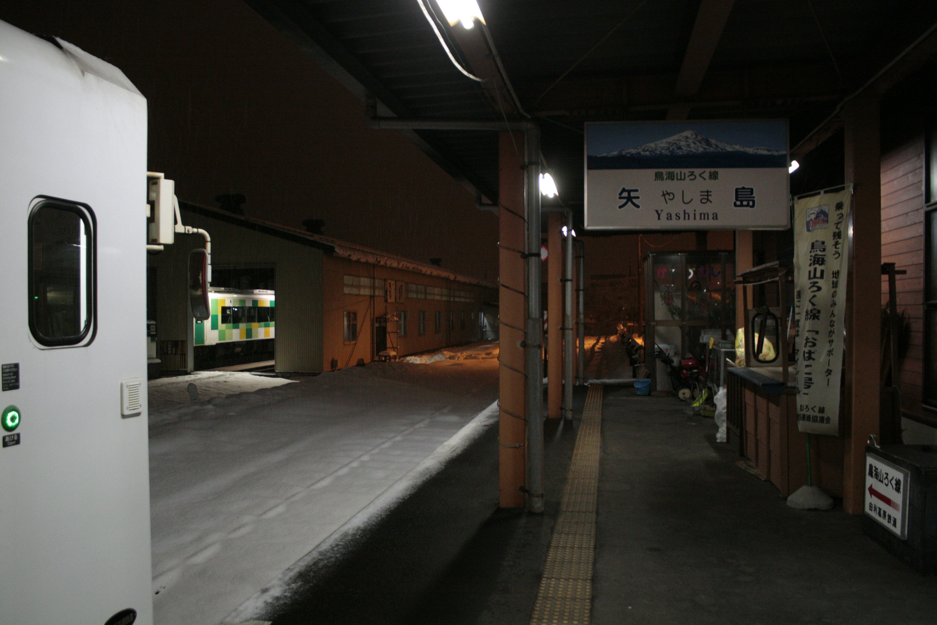 夜の駅に停車中の列車と雪のあるプラットフォーム