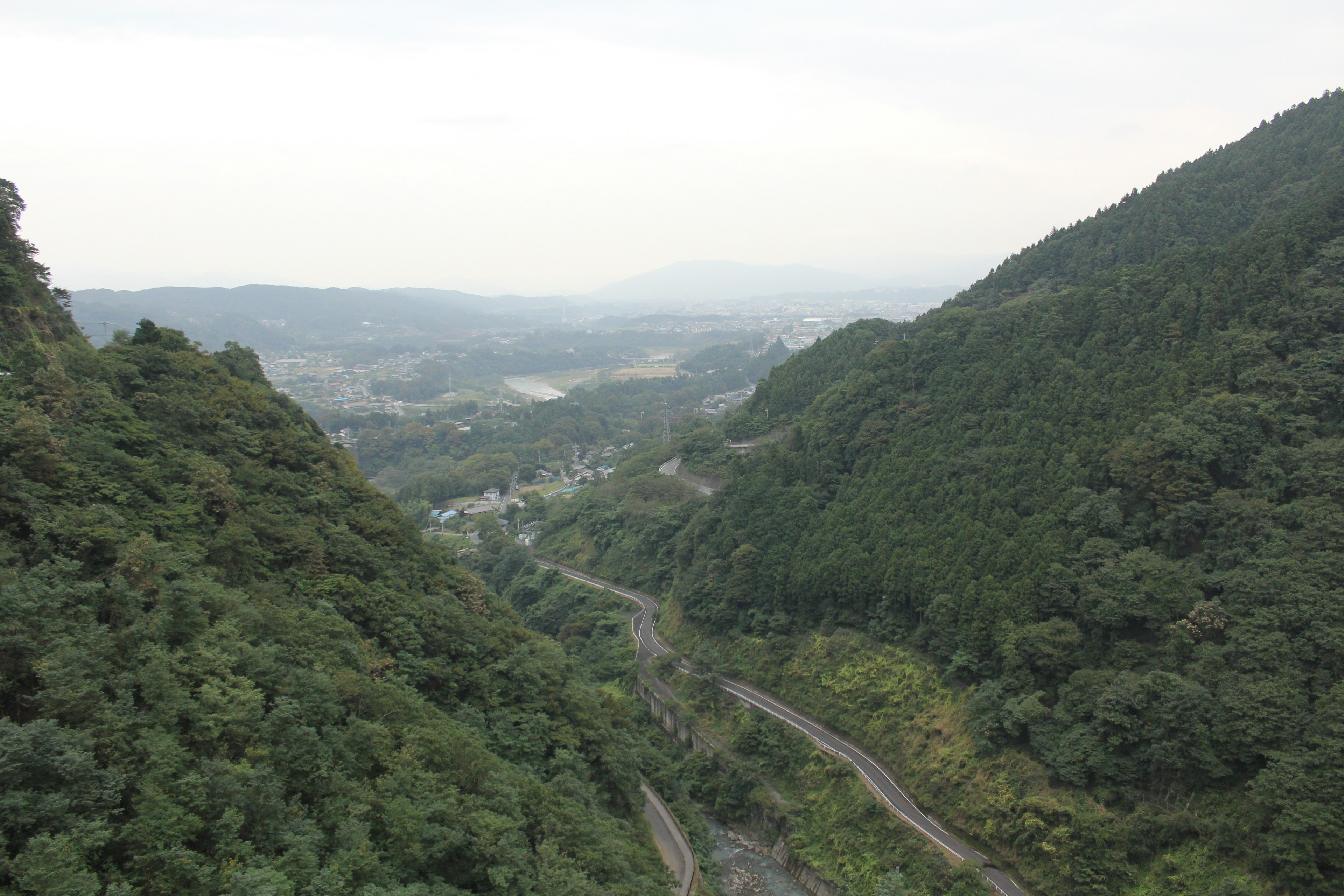 Montagne verdi che circondano un paesaggio vallivo con binari ferroviari tortuosi