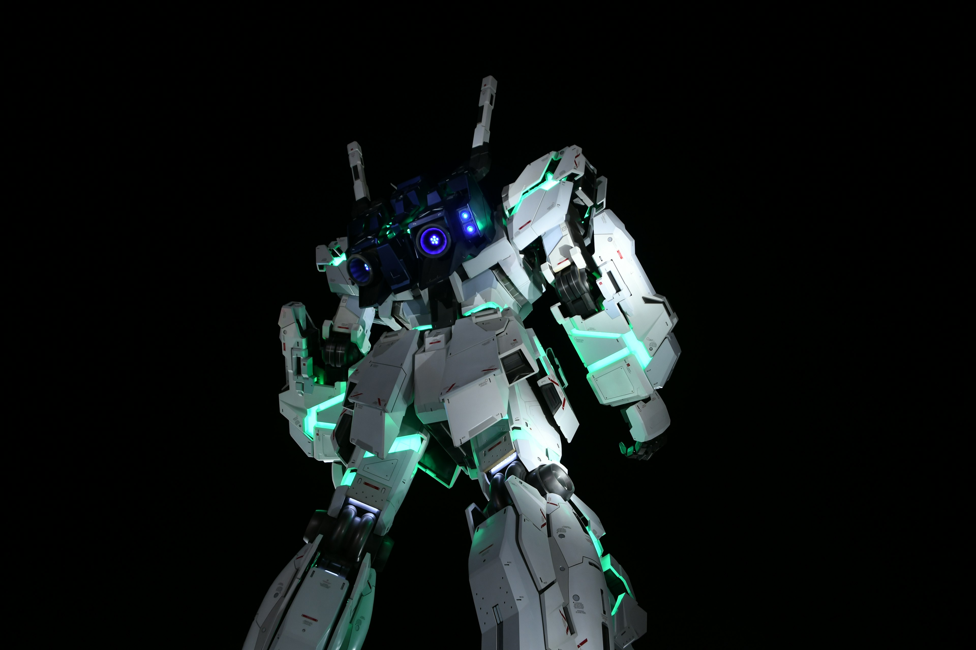 White robot with blue lights and green accents from the back