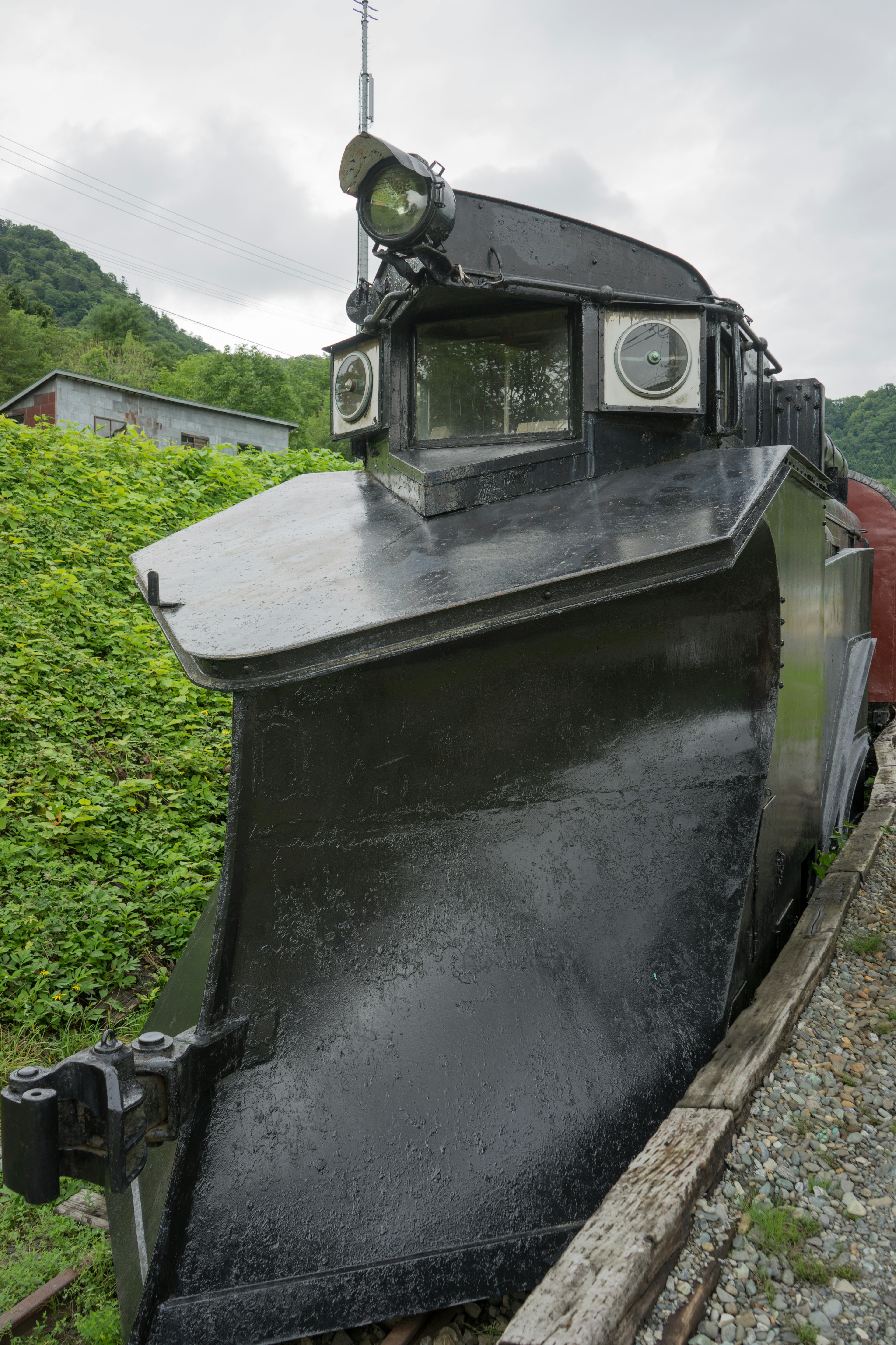 雪を除去するための黒い列車の前部が山の背景にある