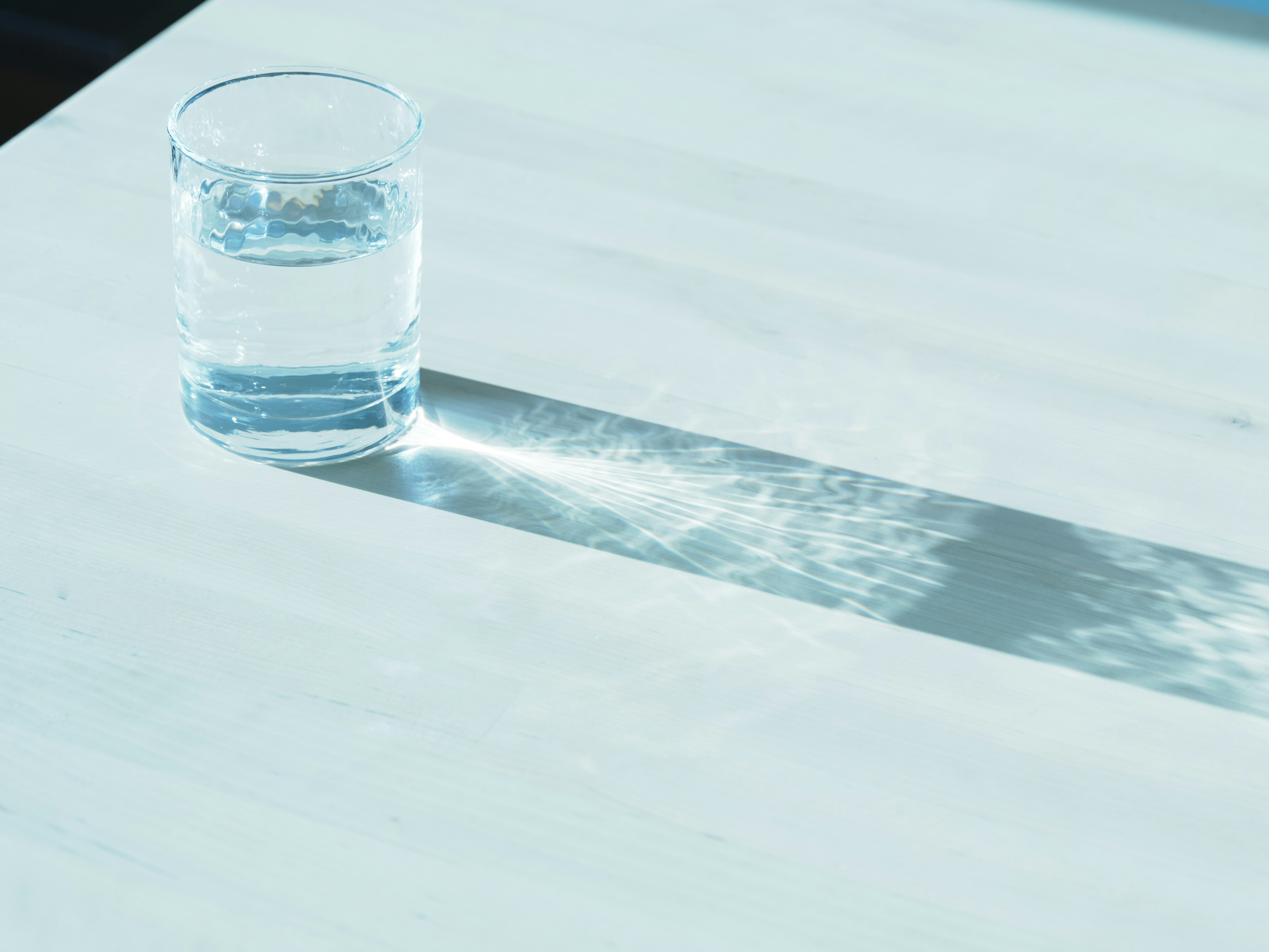 A clear glass of water casting a shadow on a surface