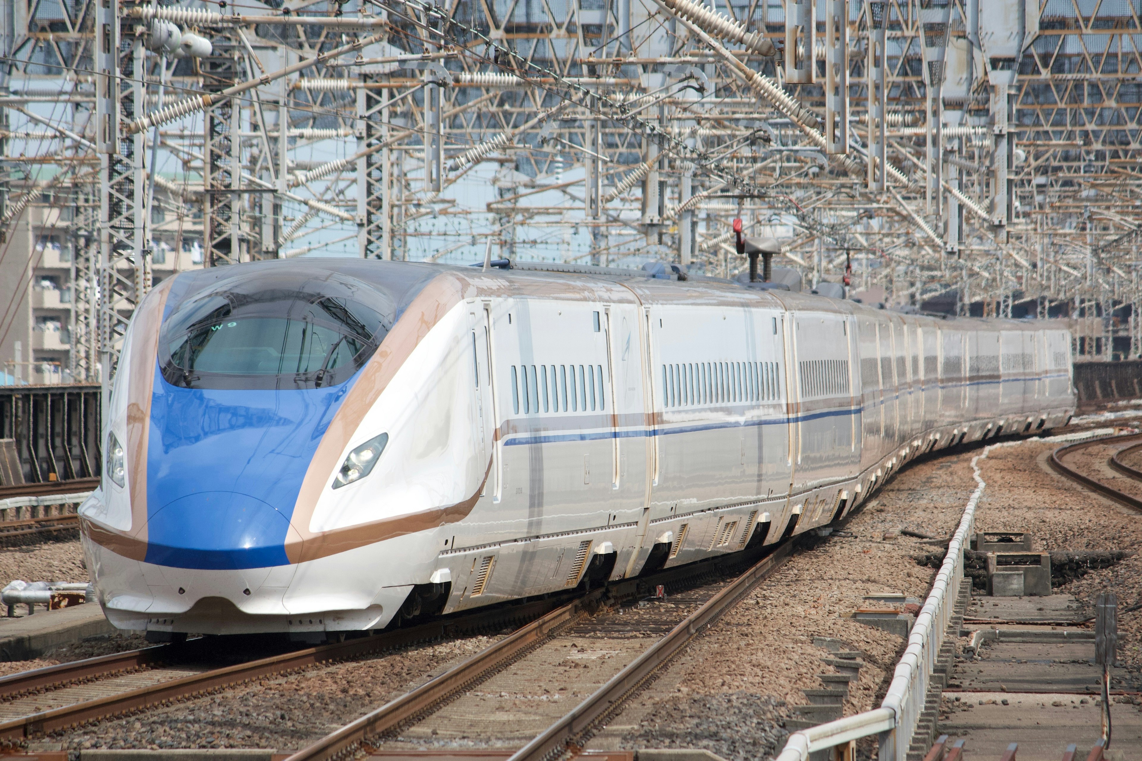 Shinkansen mit blau-weißer Gestaltung, der um eine Eisenbahnkurve fährt