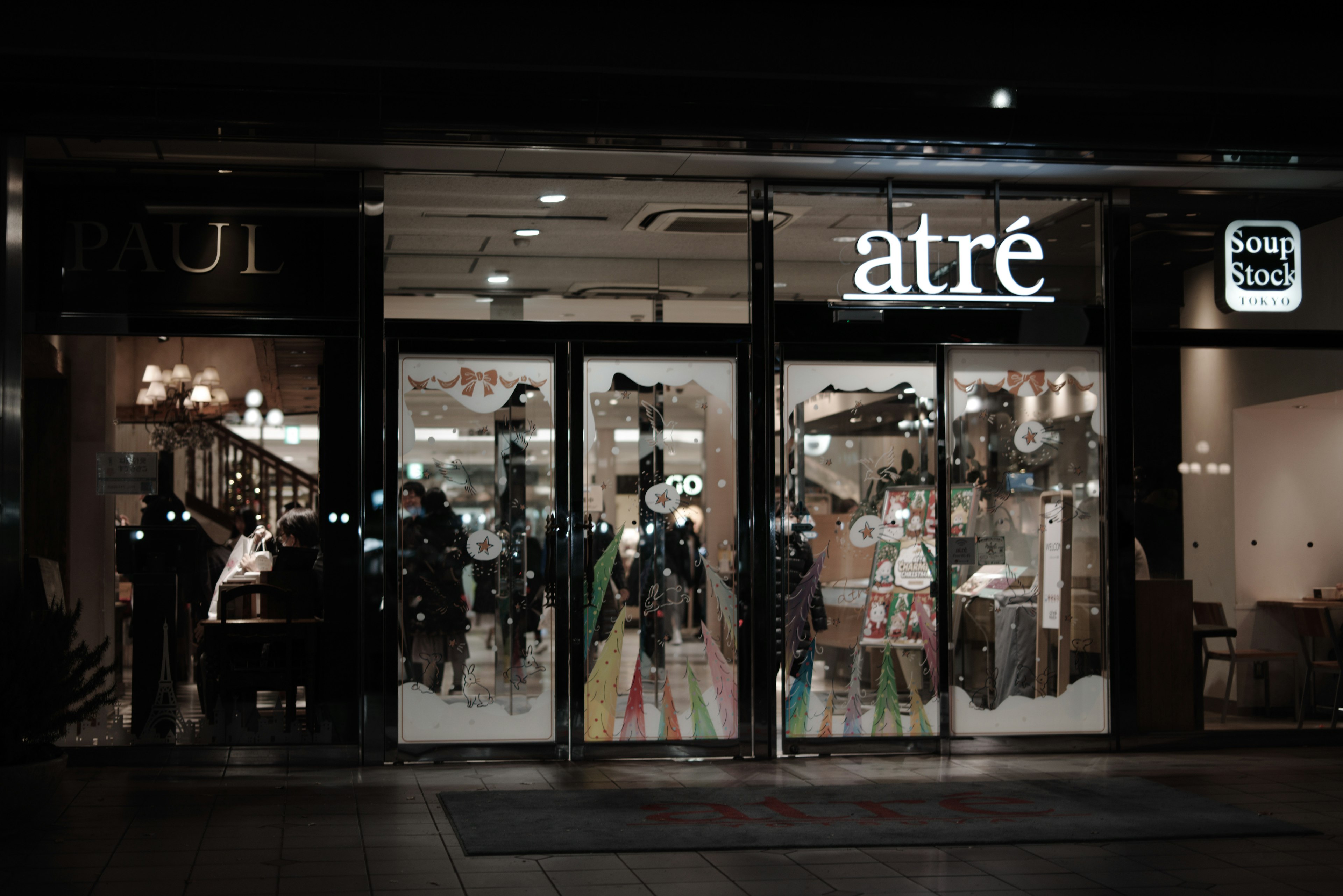 Extérieur du magasin atré avec des portes en verre illuminées et des produits colorés visibles