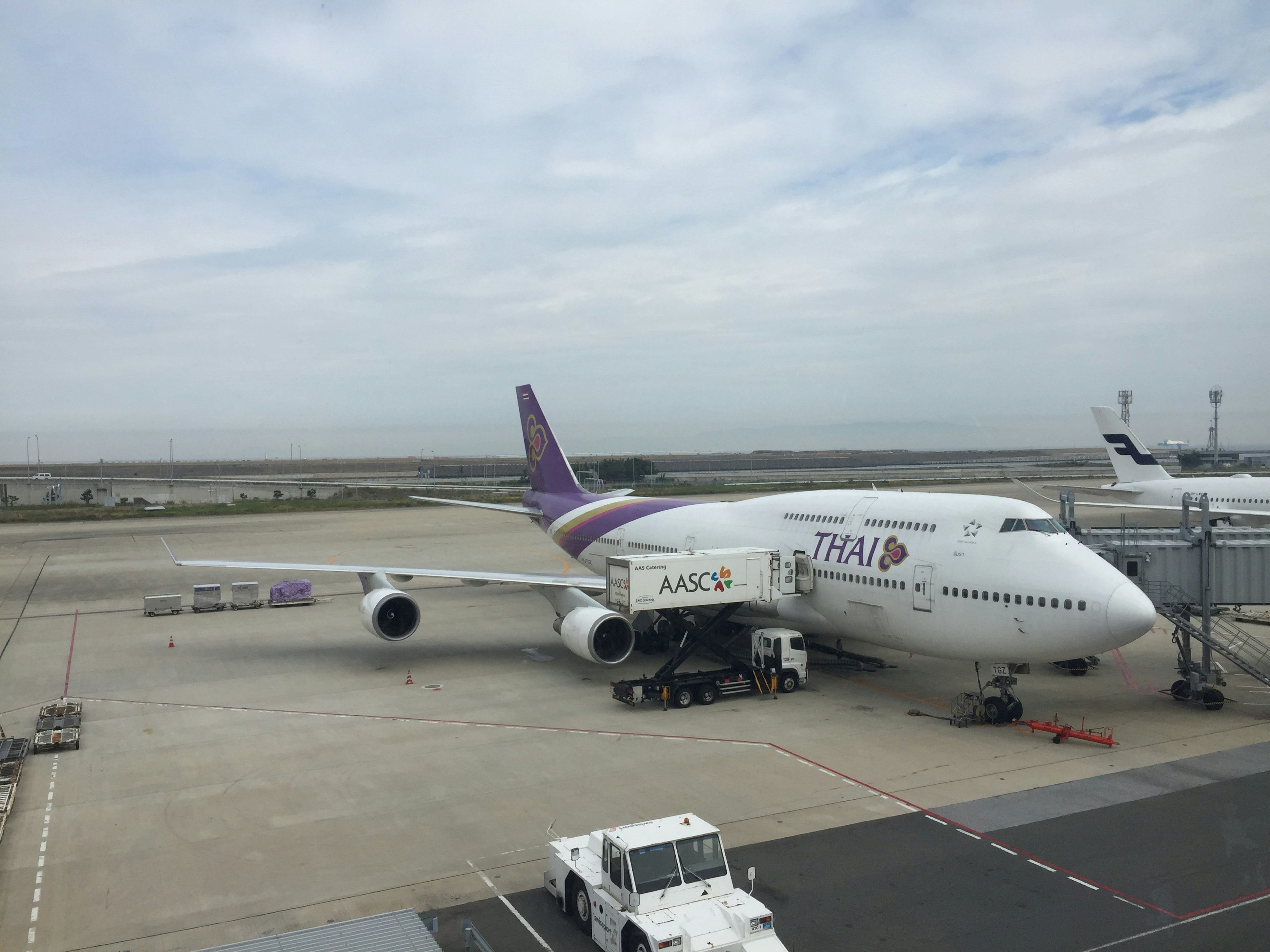 Boeing 747 Thai Airways di bandara dengan kendaraan layanan darat