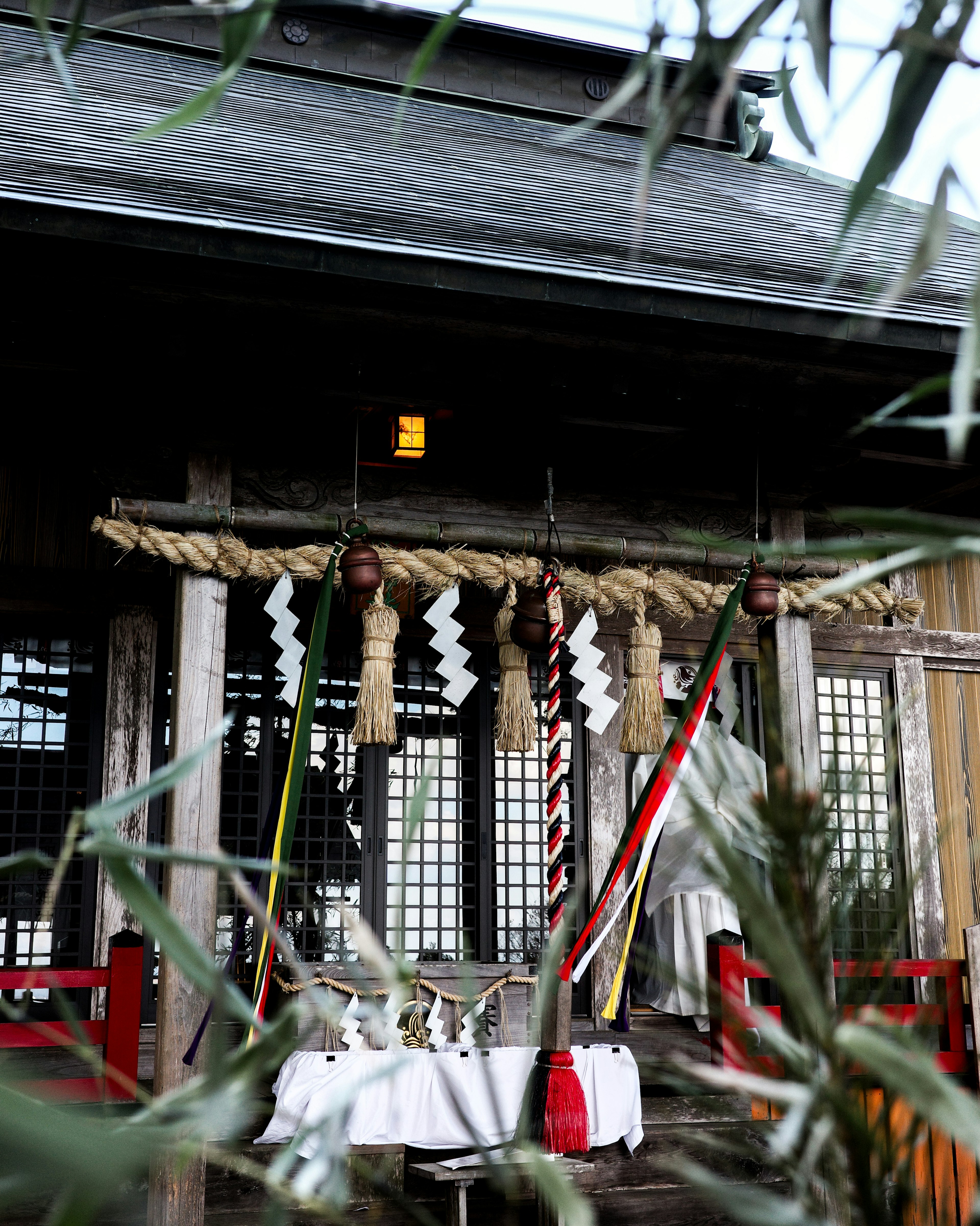 傳統神社入口的圖像，紅色柱子和裝飾性神明繩