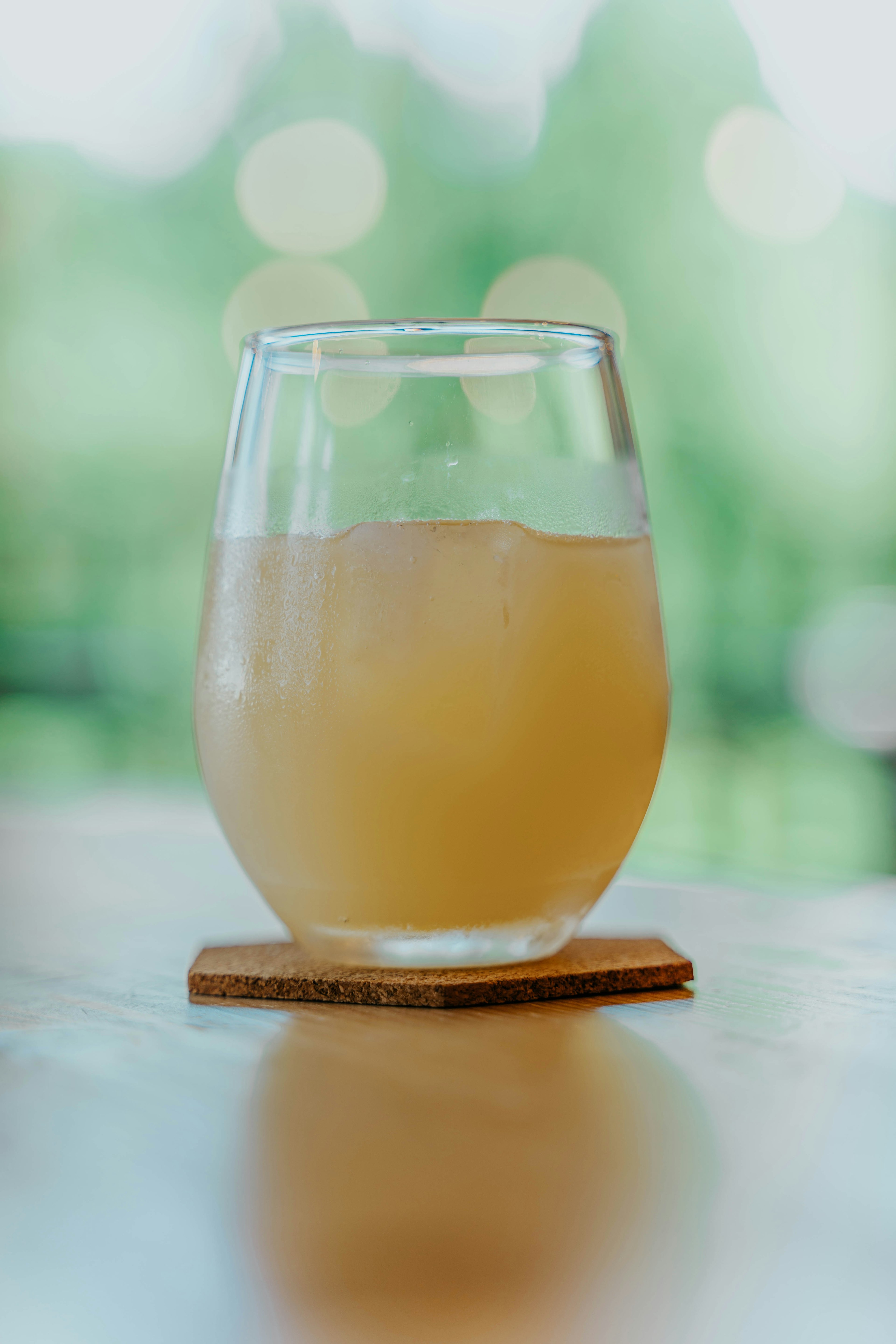 Un vaso transparente con una bebida y hielo colocado sobre una mesa