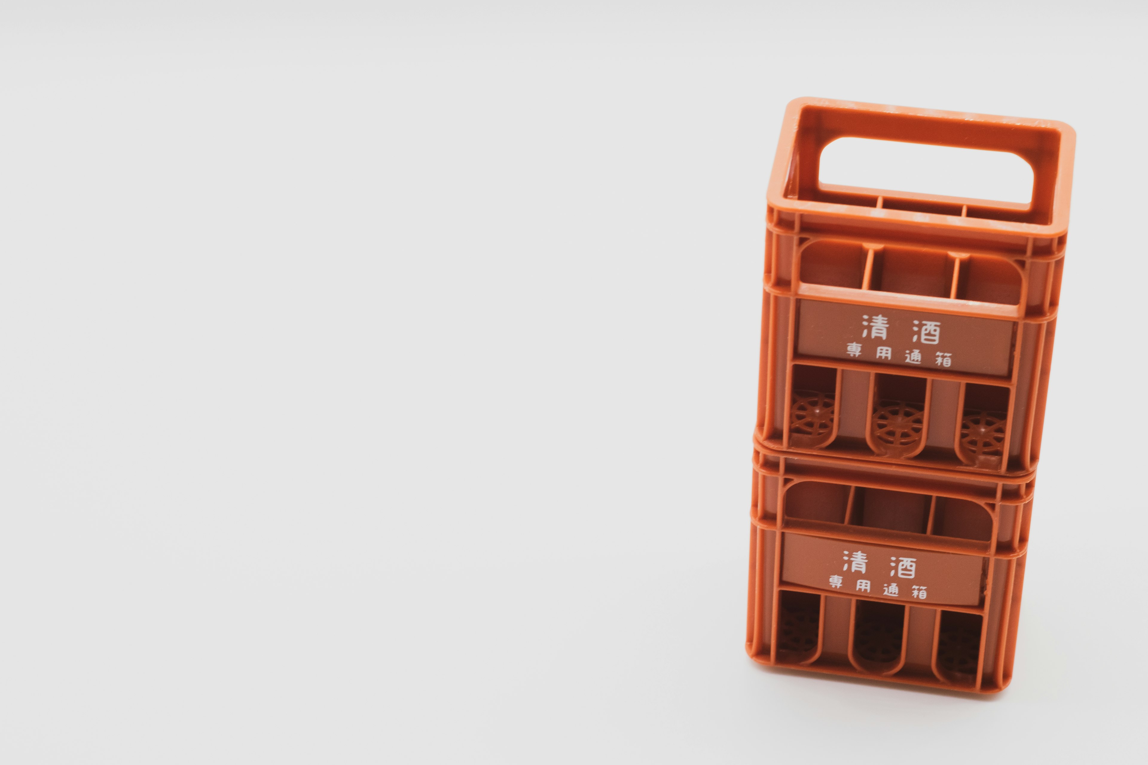 Two stacked orange plastic storage crates with handles