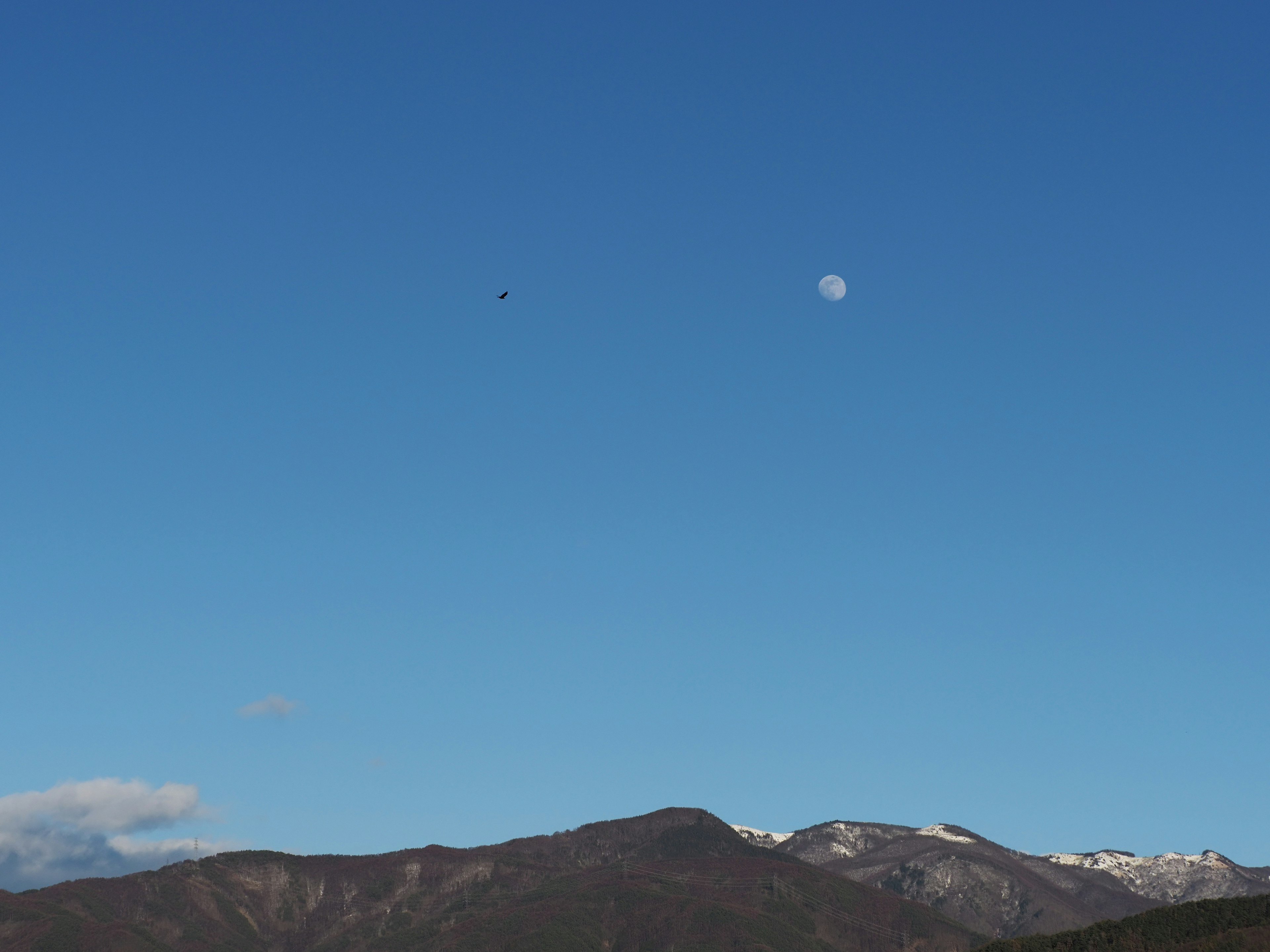 Eine Landschaft mit klarem blauen Himmel und schneebedeckten Bergen mit einer Wolke