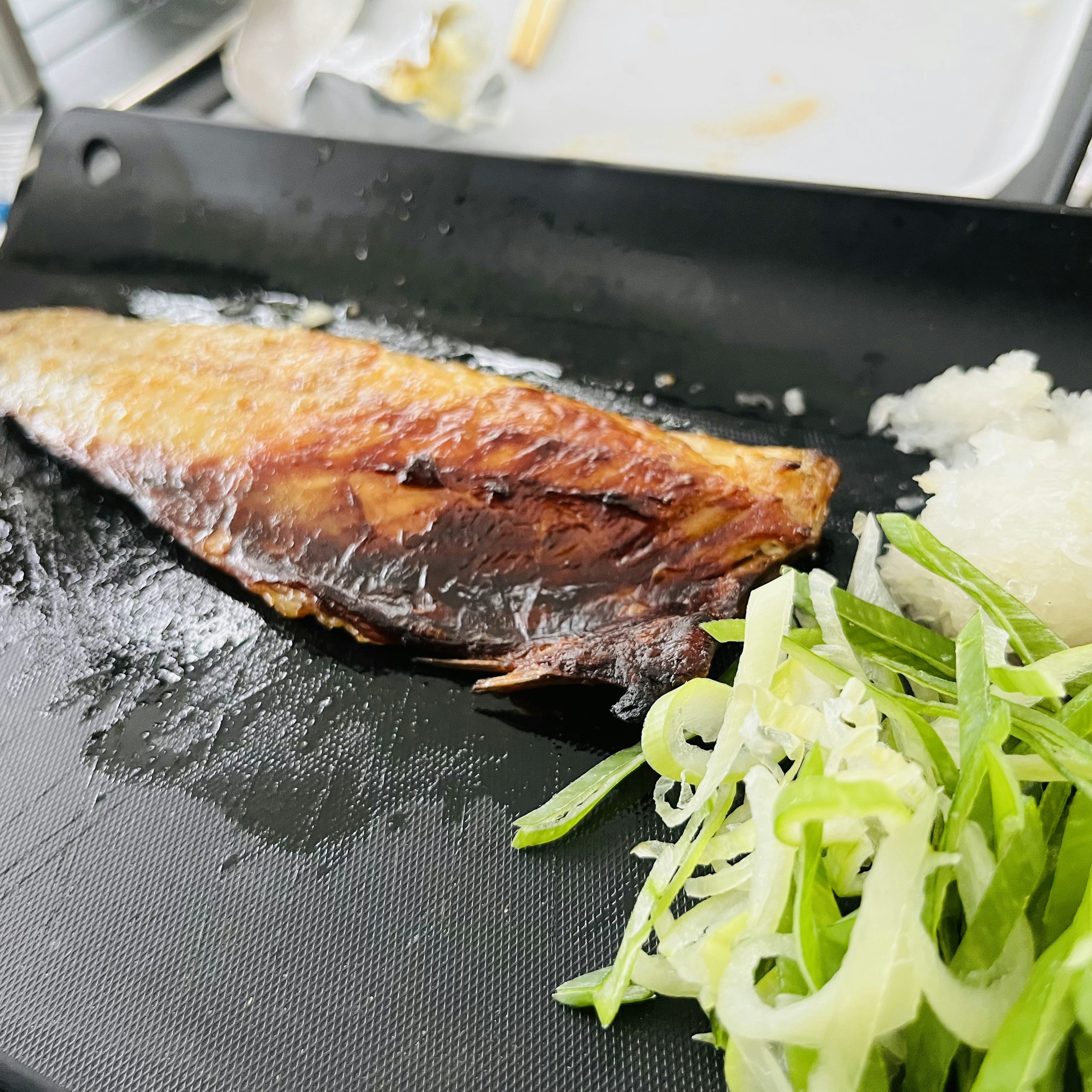 Pesce grigliato servito con cipolle verdi e daikon grattugiato