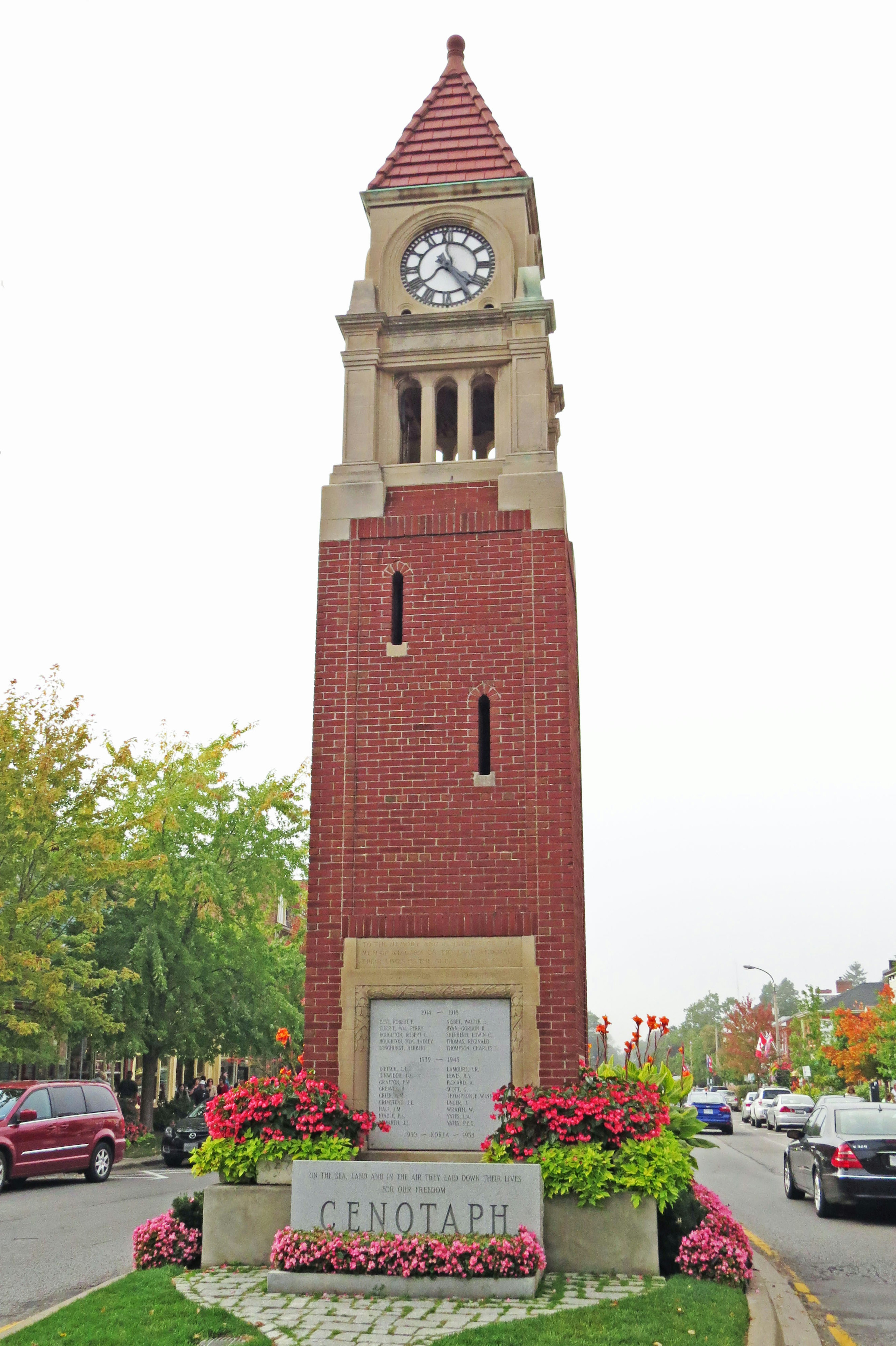 Brick clock tower surrounded by colorful flowers