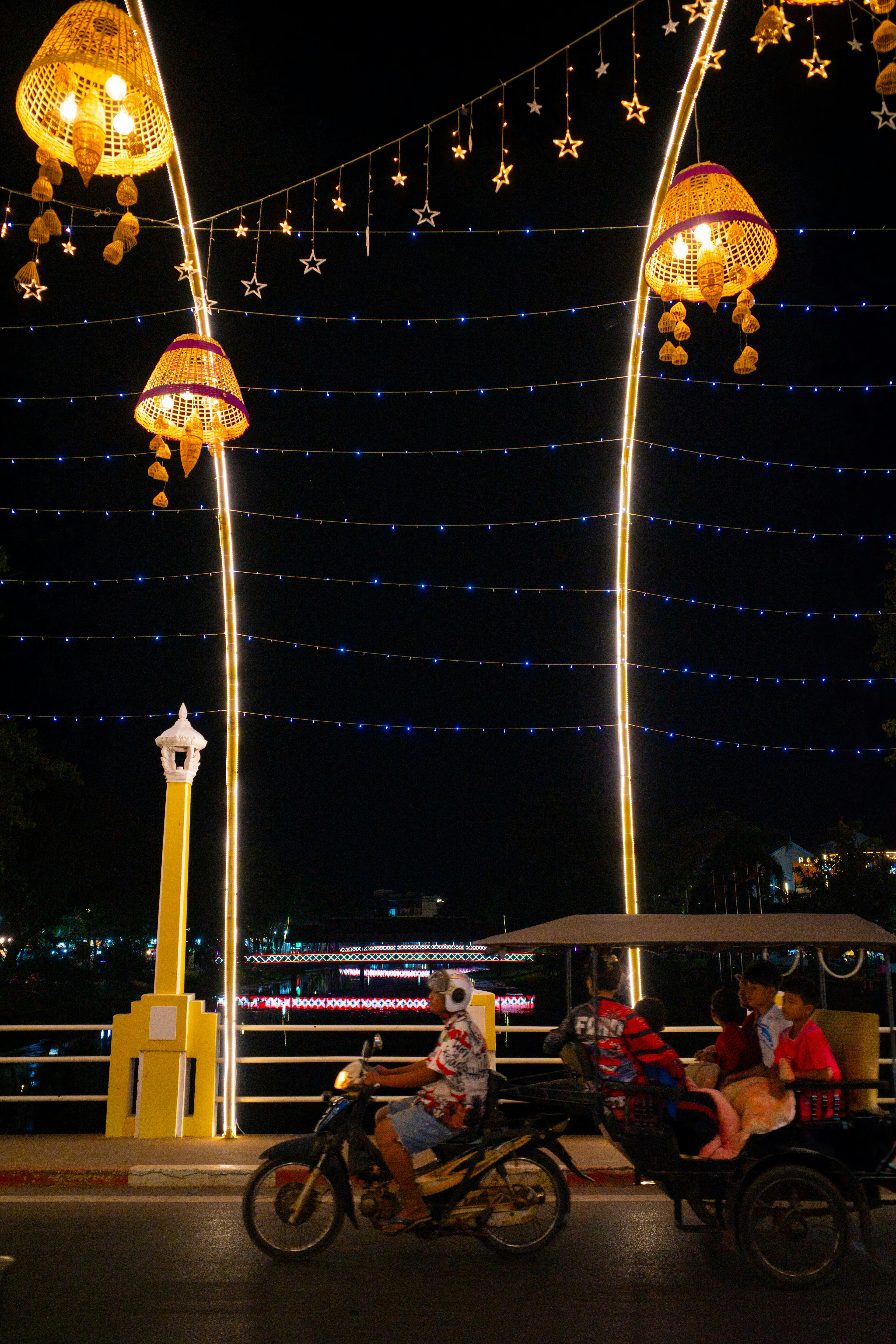 Tricycle riding through a decorated street at night with lanterns