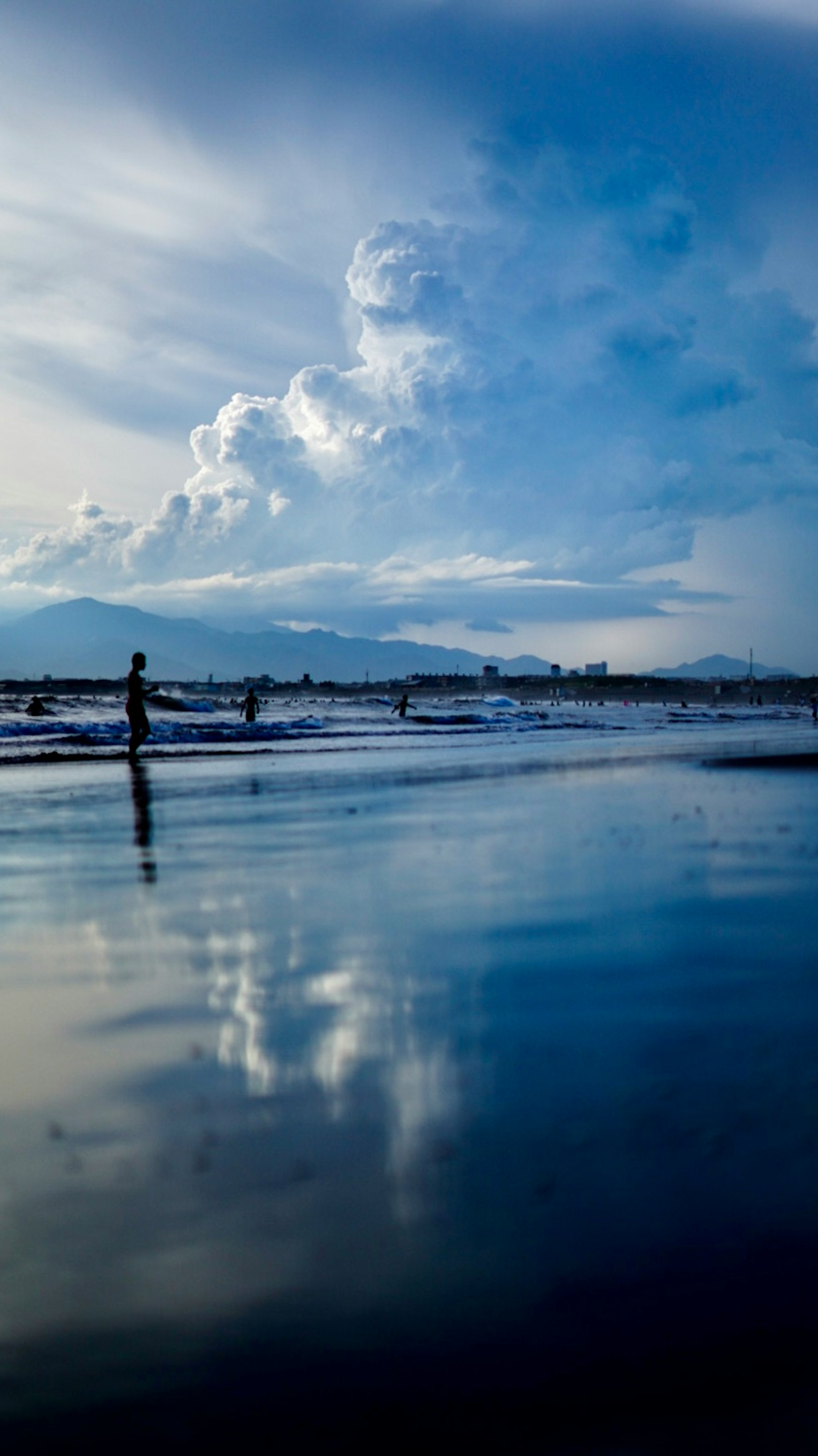 Serene beach scene with blue sea and sky person standing by the water