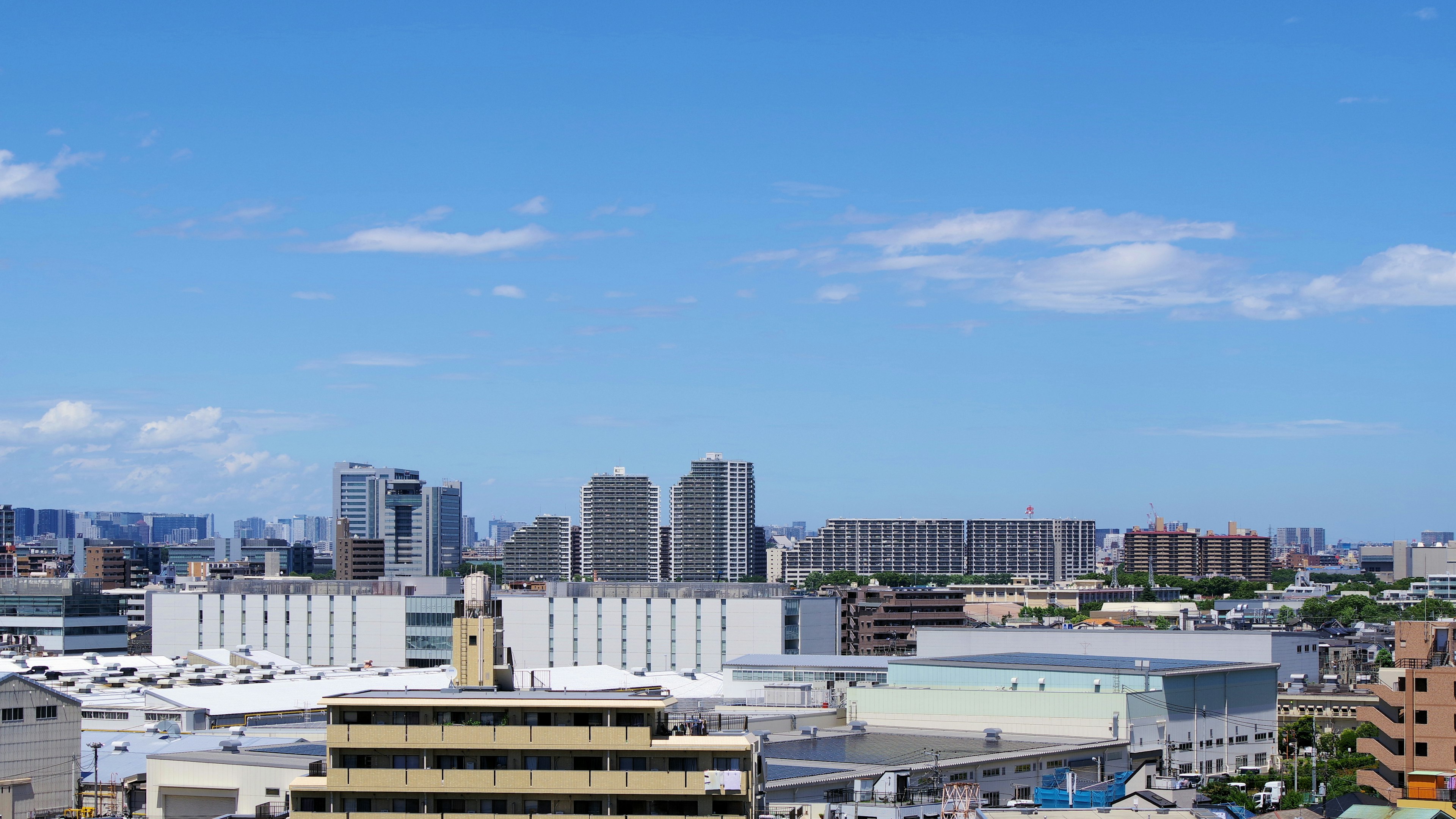 Urban landscape under a blue sky featuring a mix of high-rise buildings and low structures