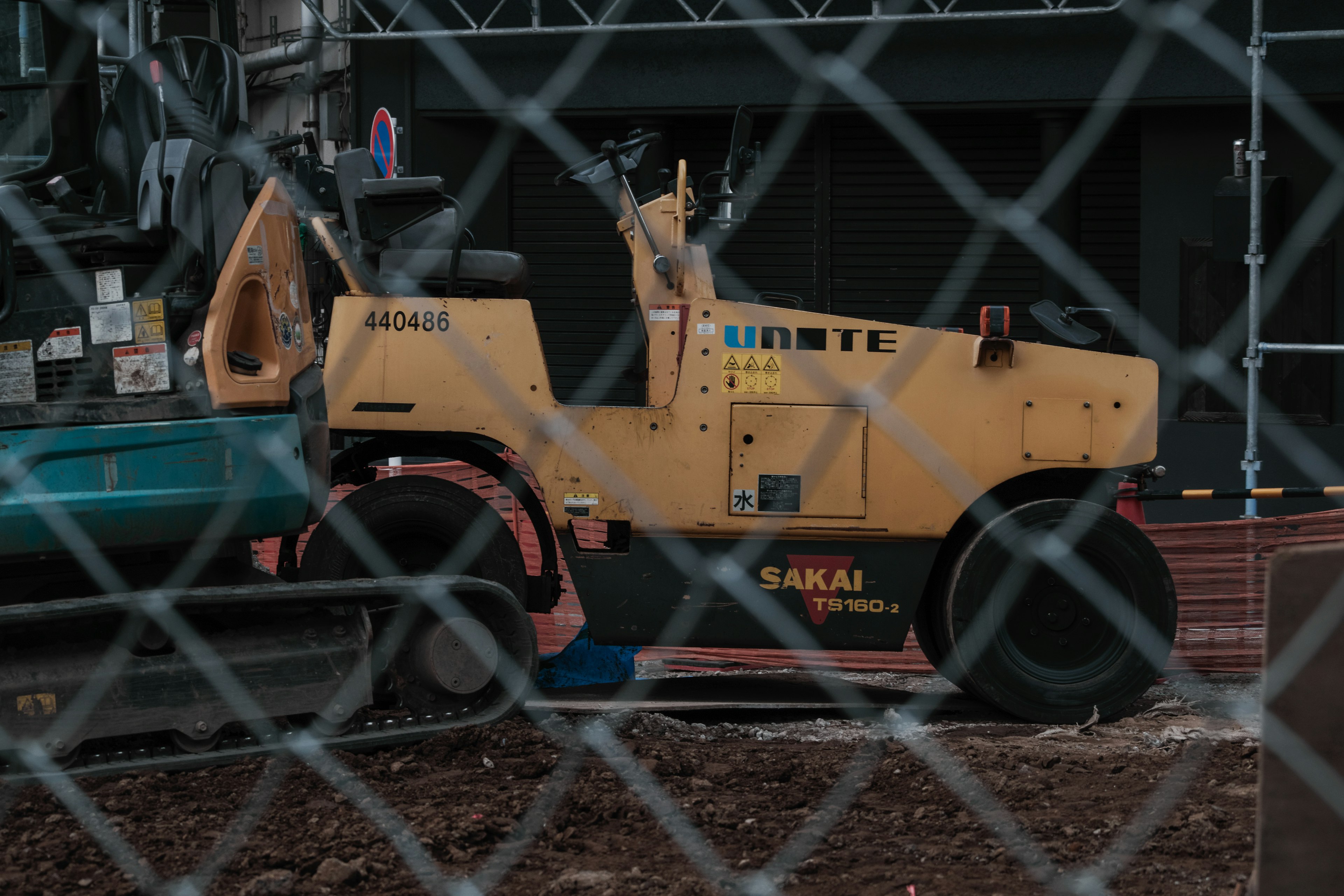 Construction site with a yellow roller and a fence