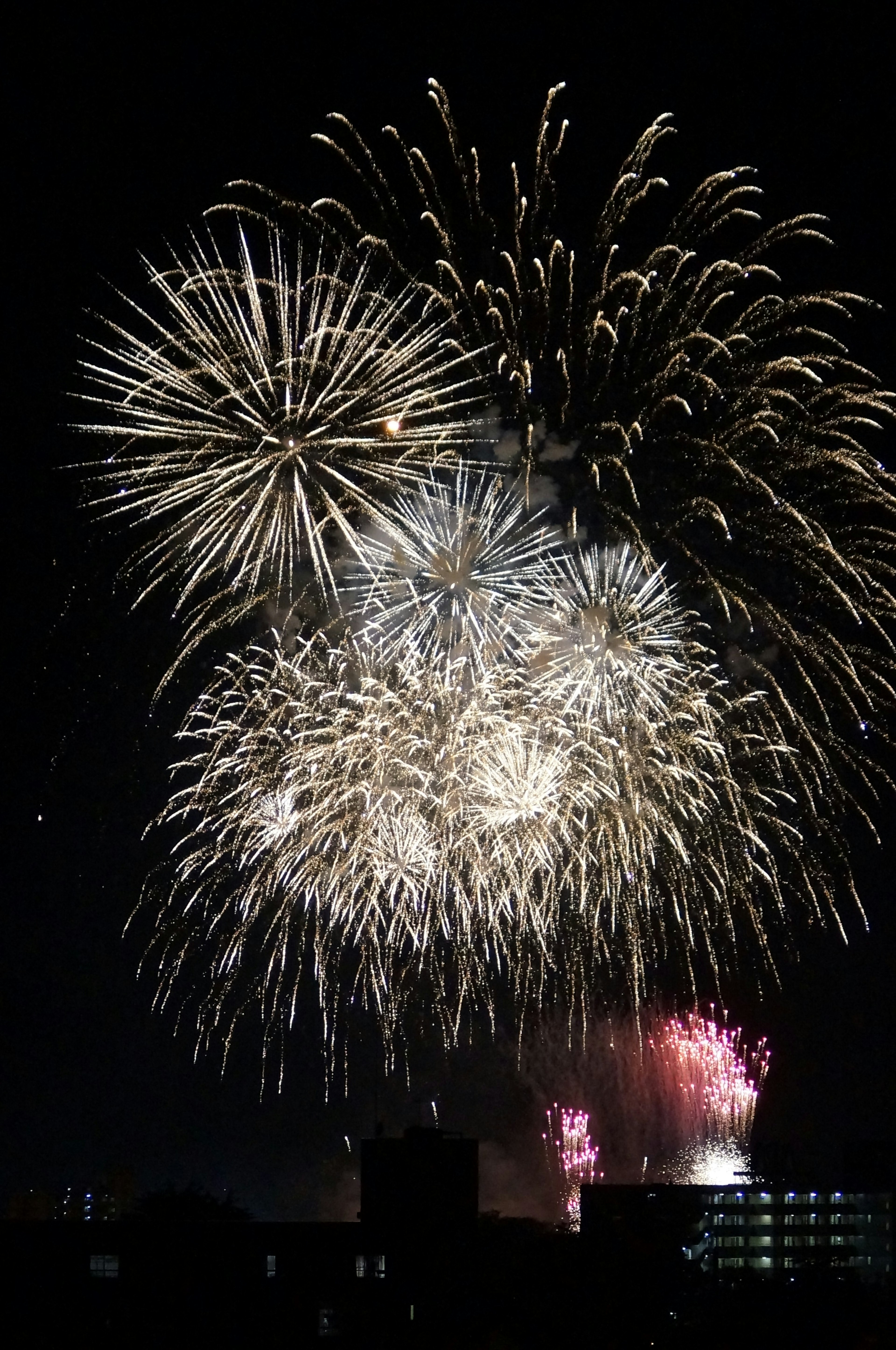 夜空中盛大的煙花表演，大型白色煙花和小型彩色煙花