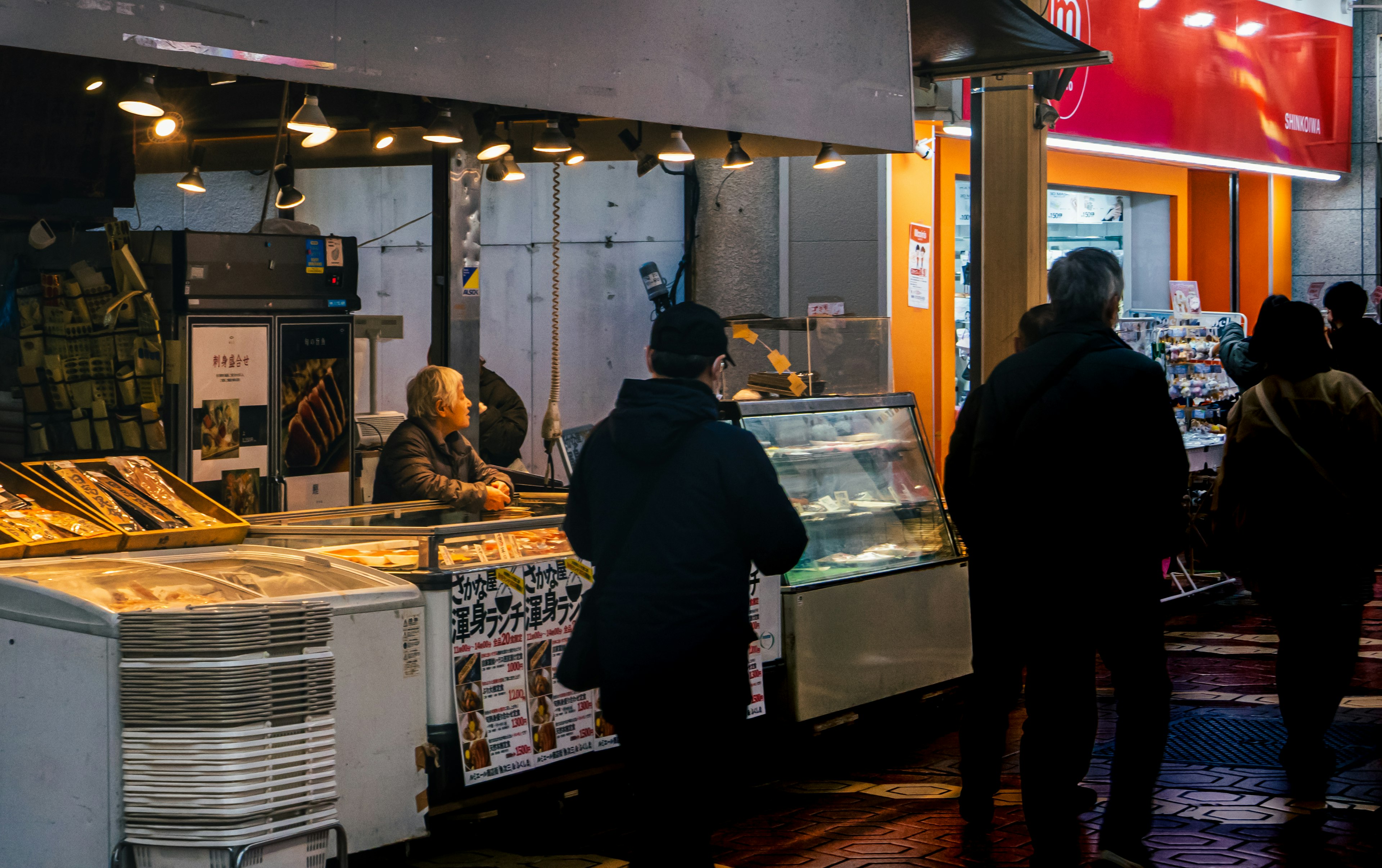 Nighttime scene of a food stall with people buying and selling