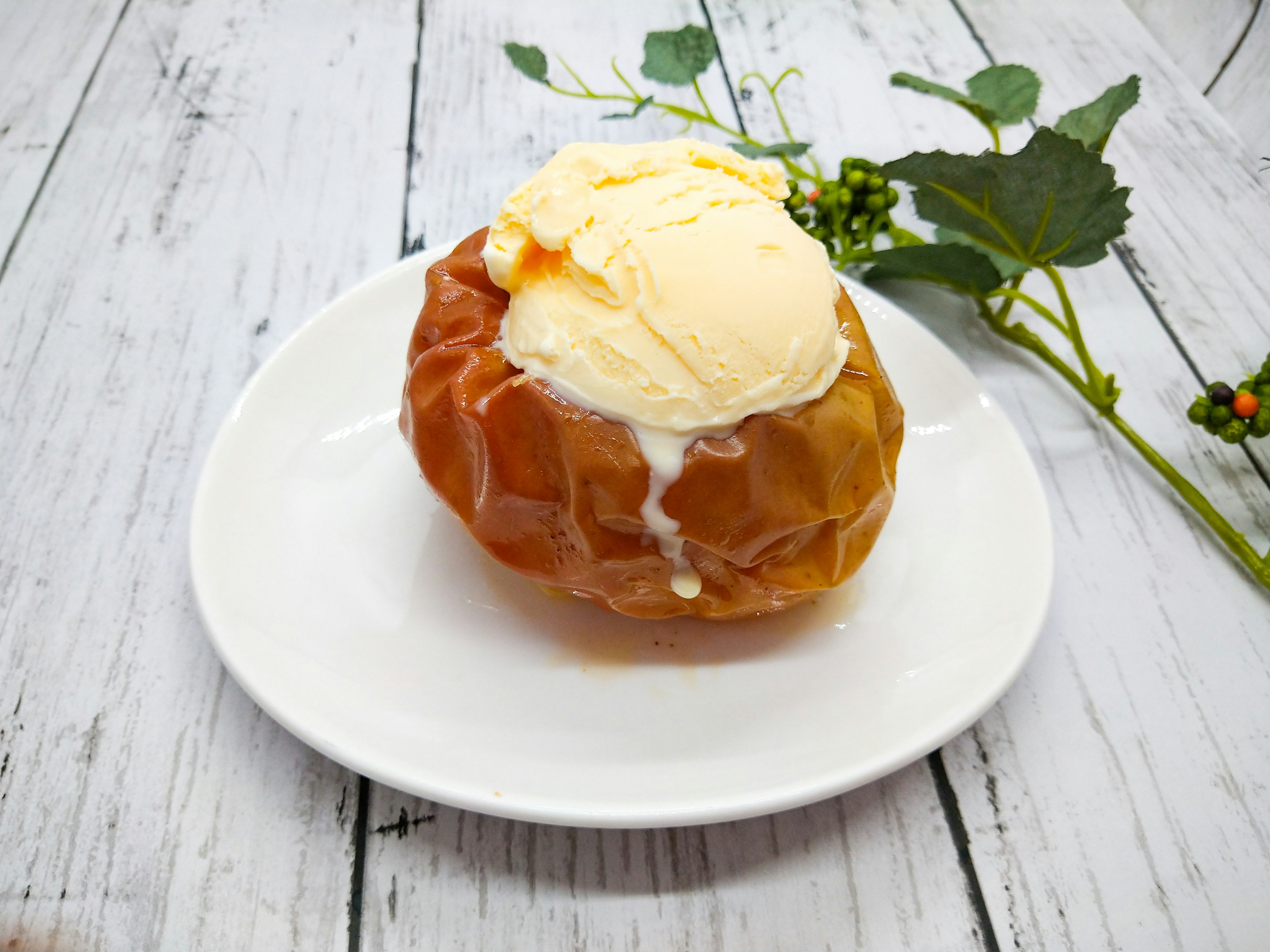 Dessert de pomme au four surmonté de crème glacée servi dans une assiette blanche