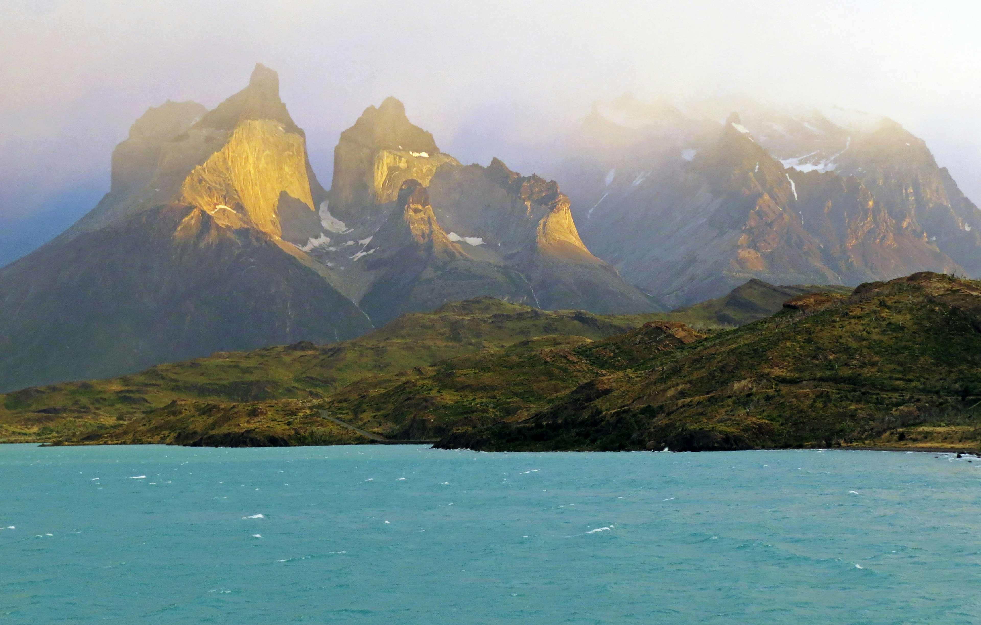 Vista escénica de montañas brumosas con agua turquesa