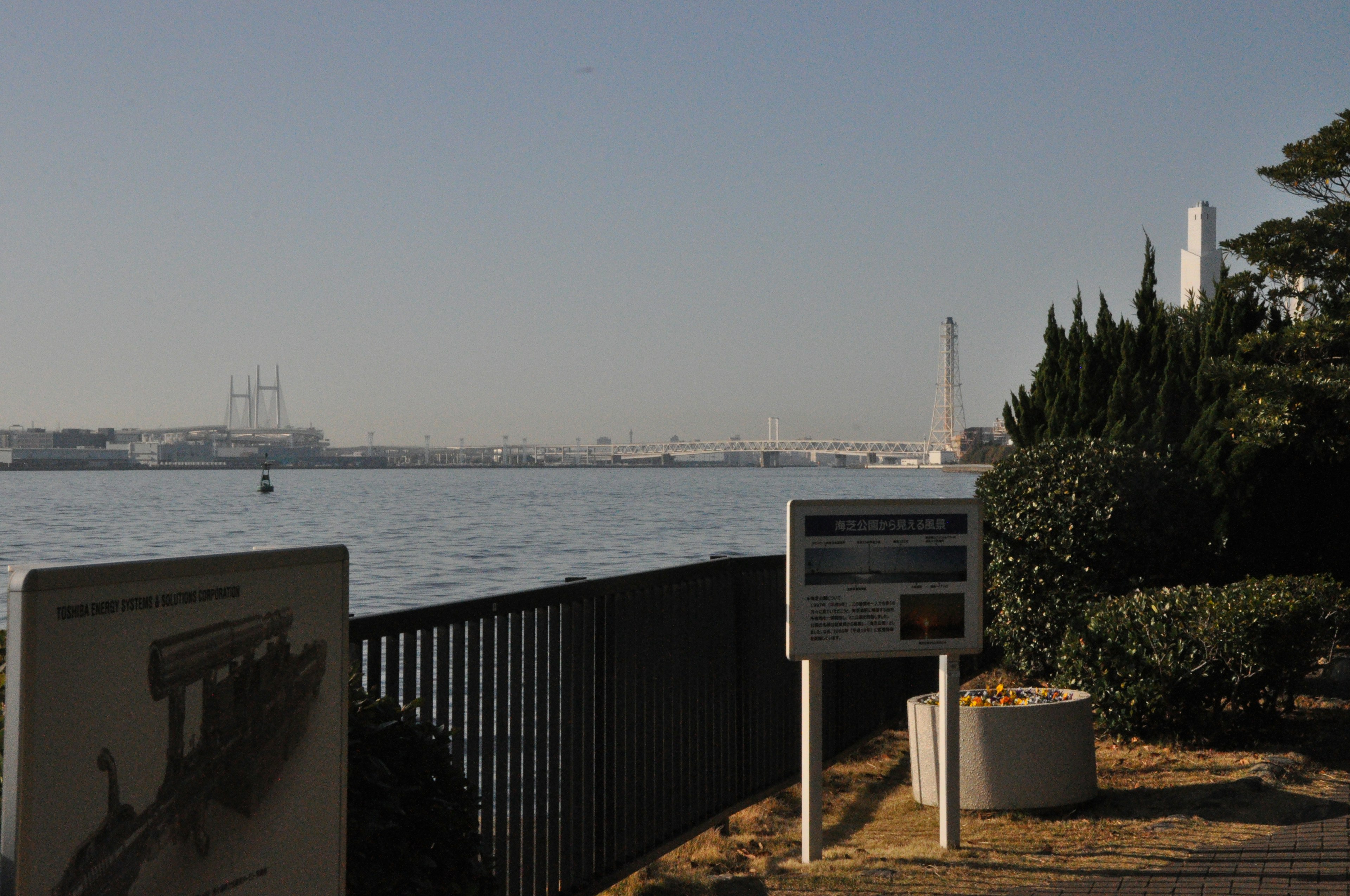 Promenade au bord de la mer avec paysage industriel et panneaux d'information