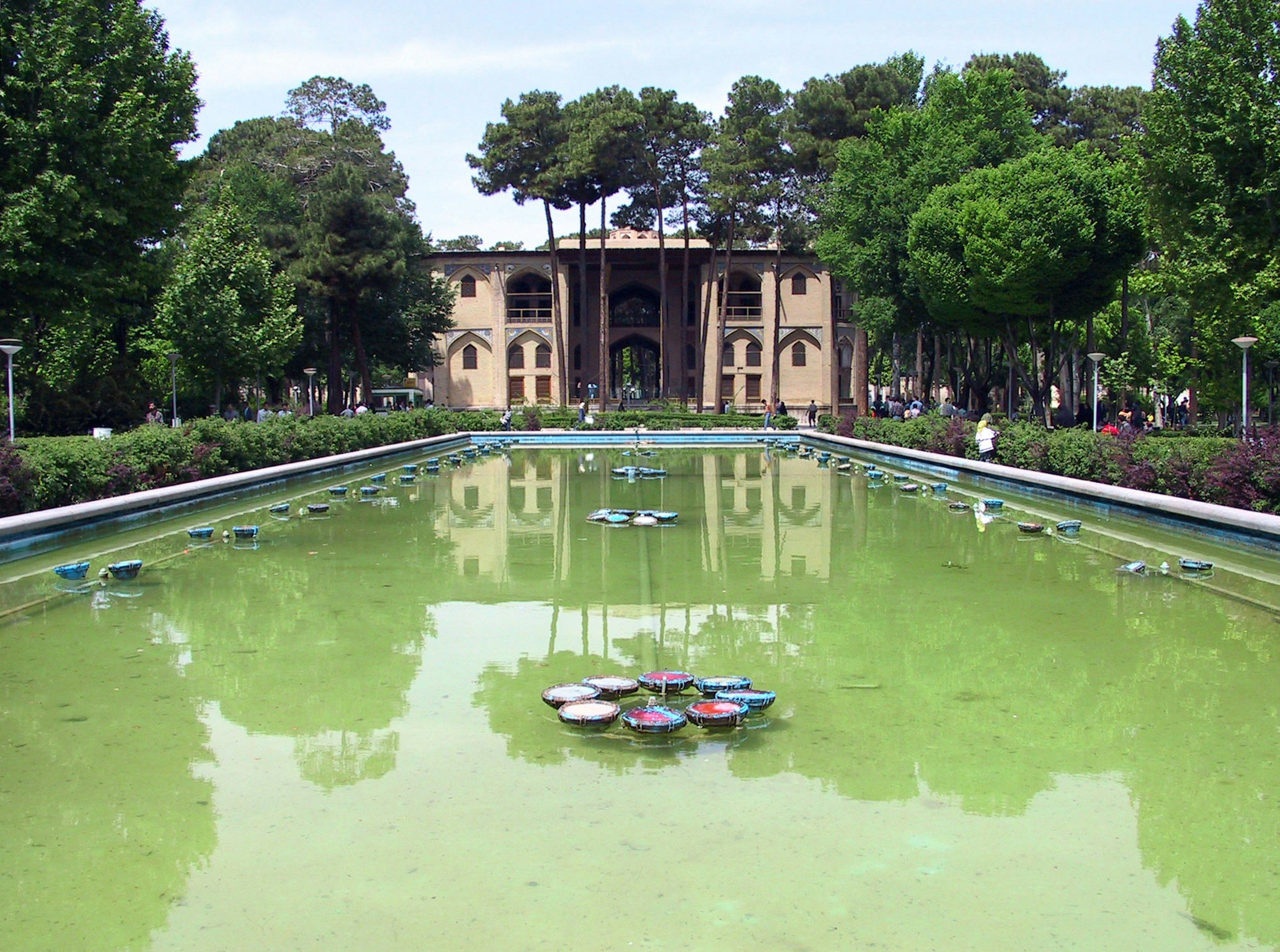 Serene park pond with green water and historical building in the background