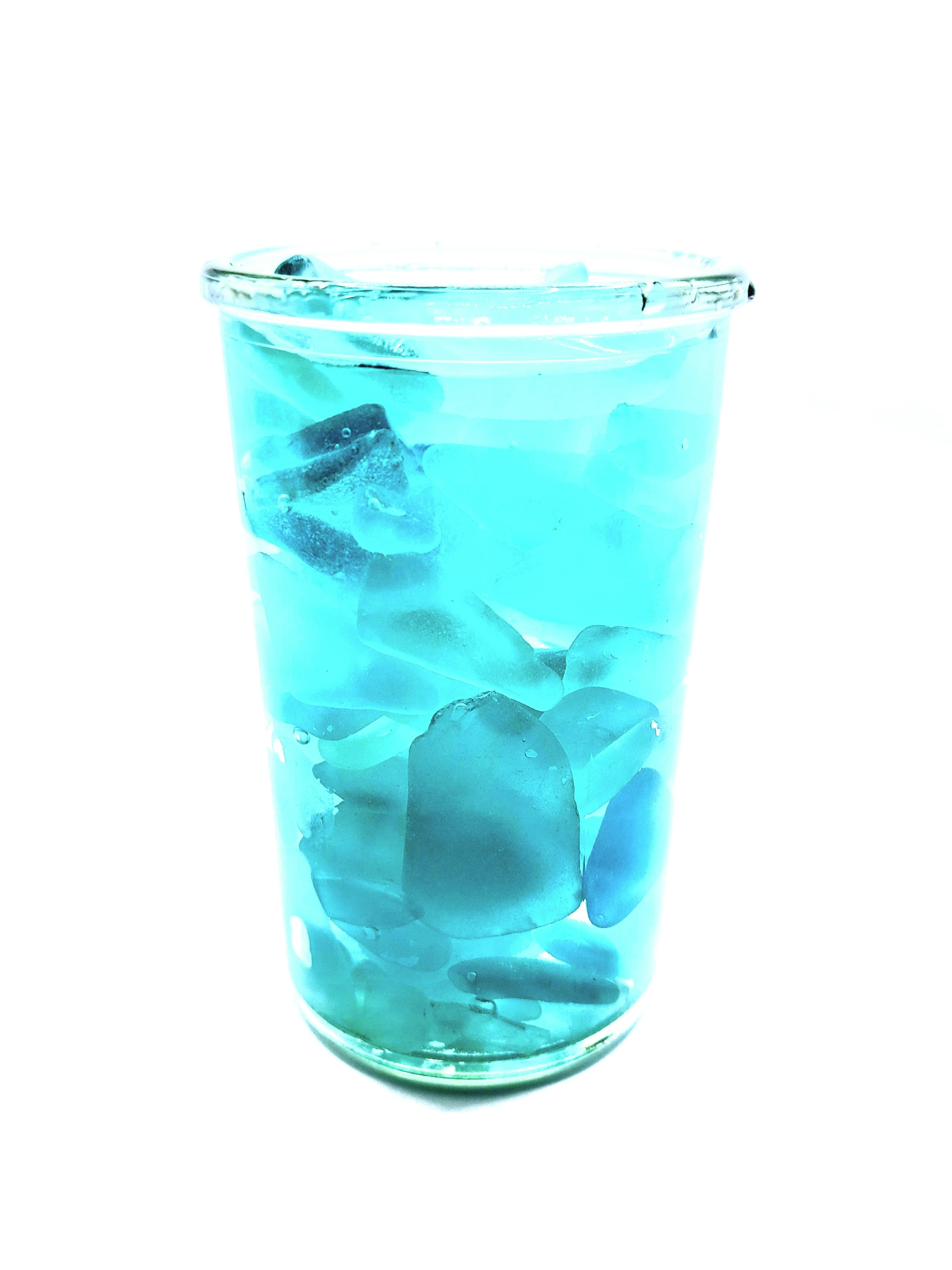 A glass filled with a blue drink and ice cubes