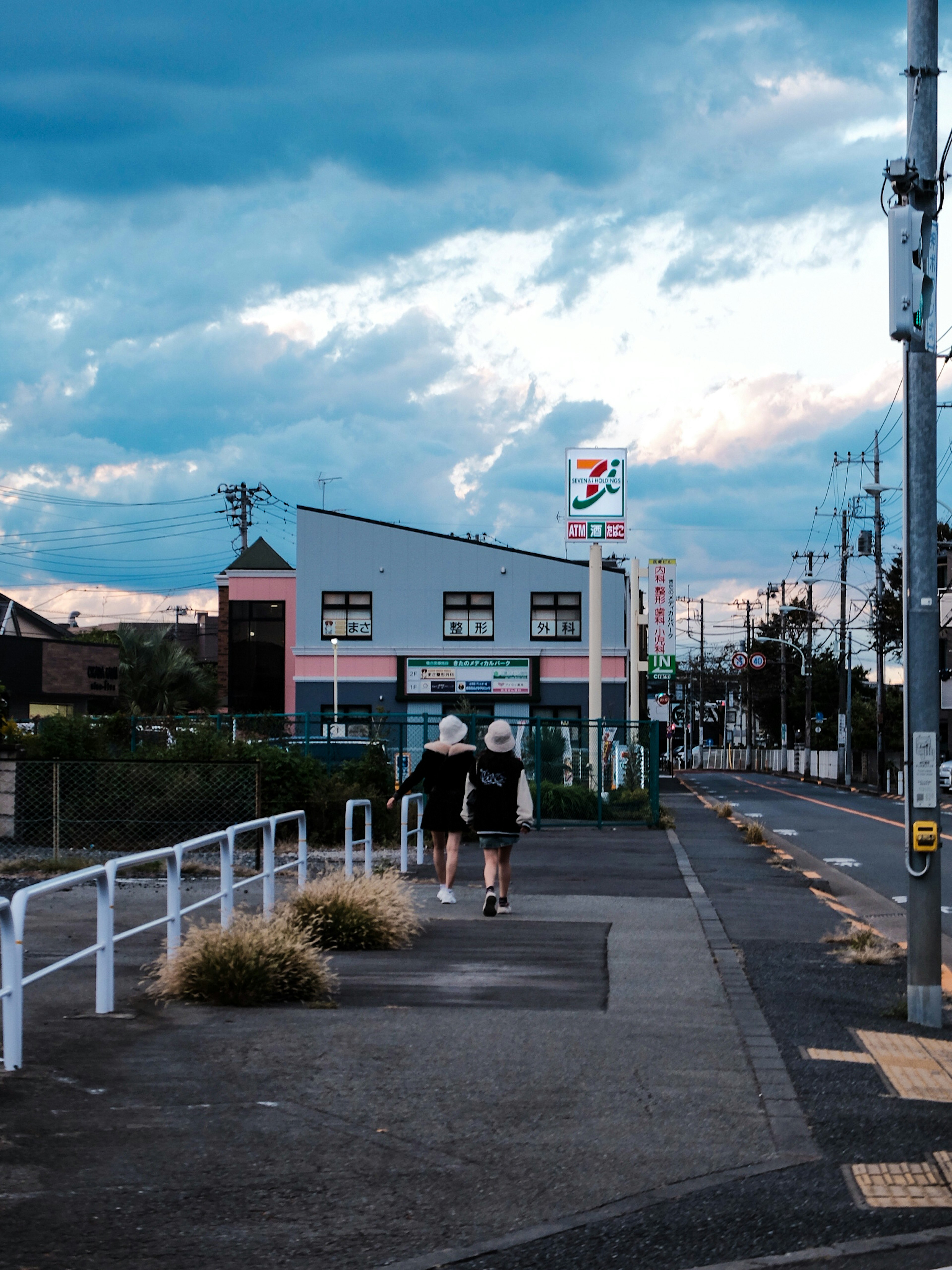 Two people walking down a quiet street with a colorful building